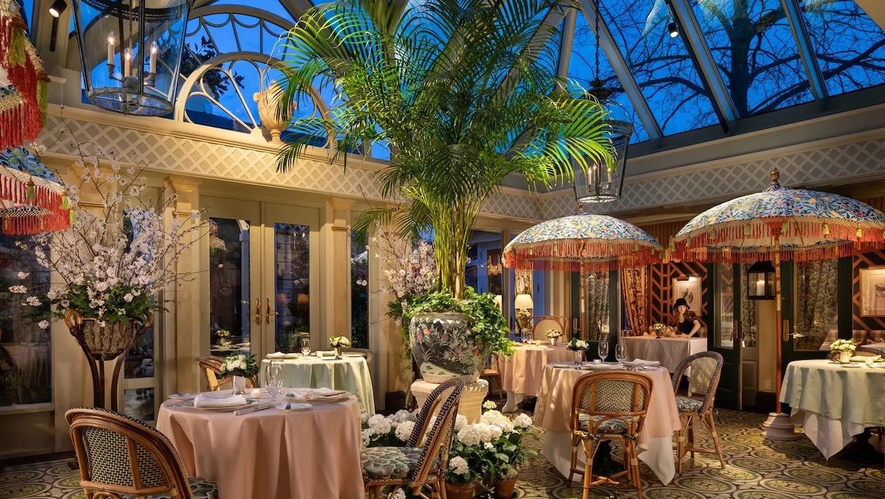 An ornate garden room at the Inn at Little Washington with potted palm trees and umbrellas over tables