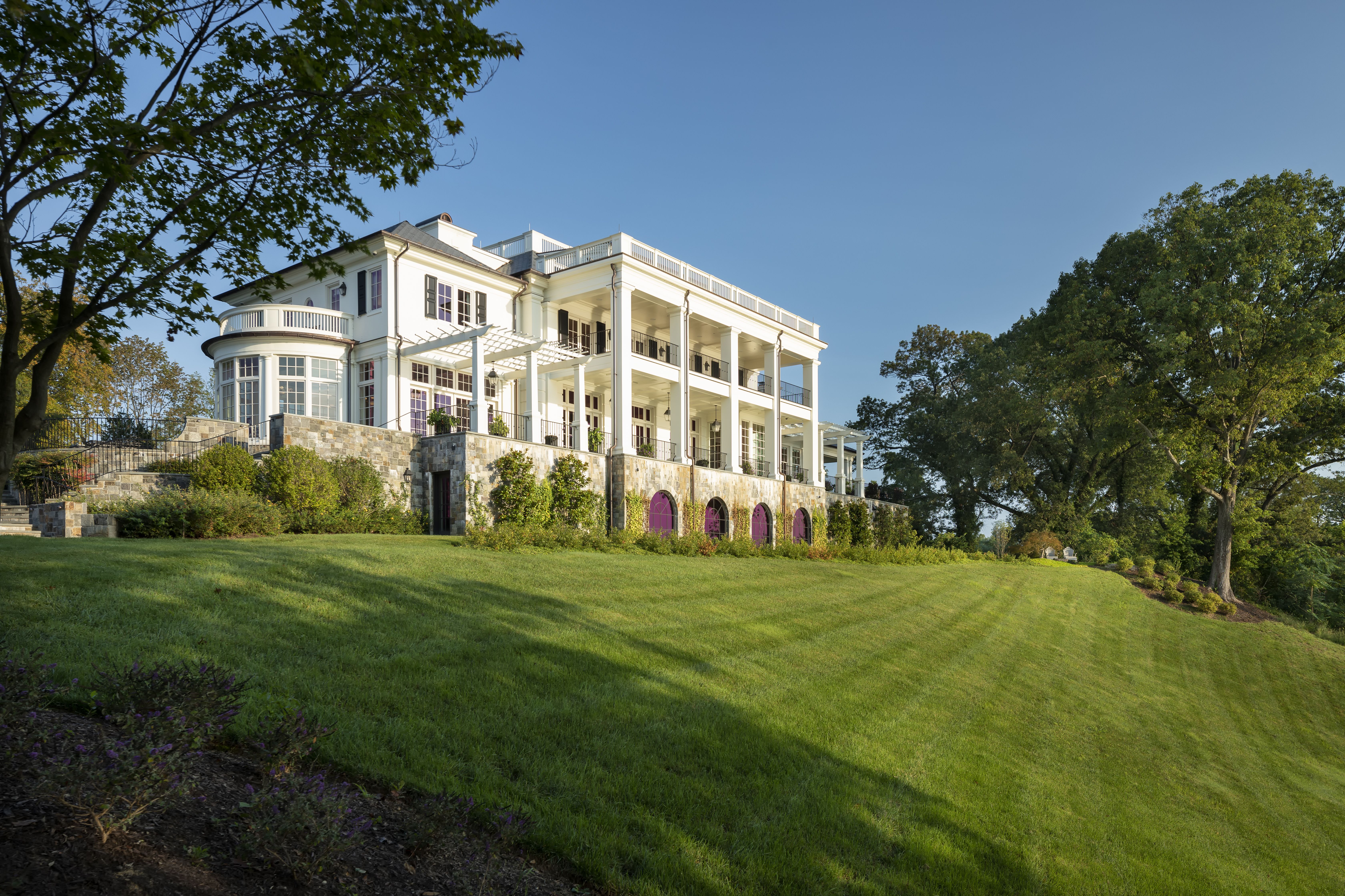 The rear facade of a white mansion with multiple porches and terraces.