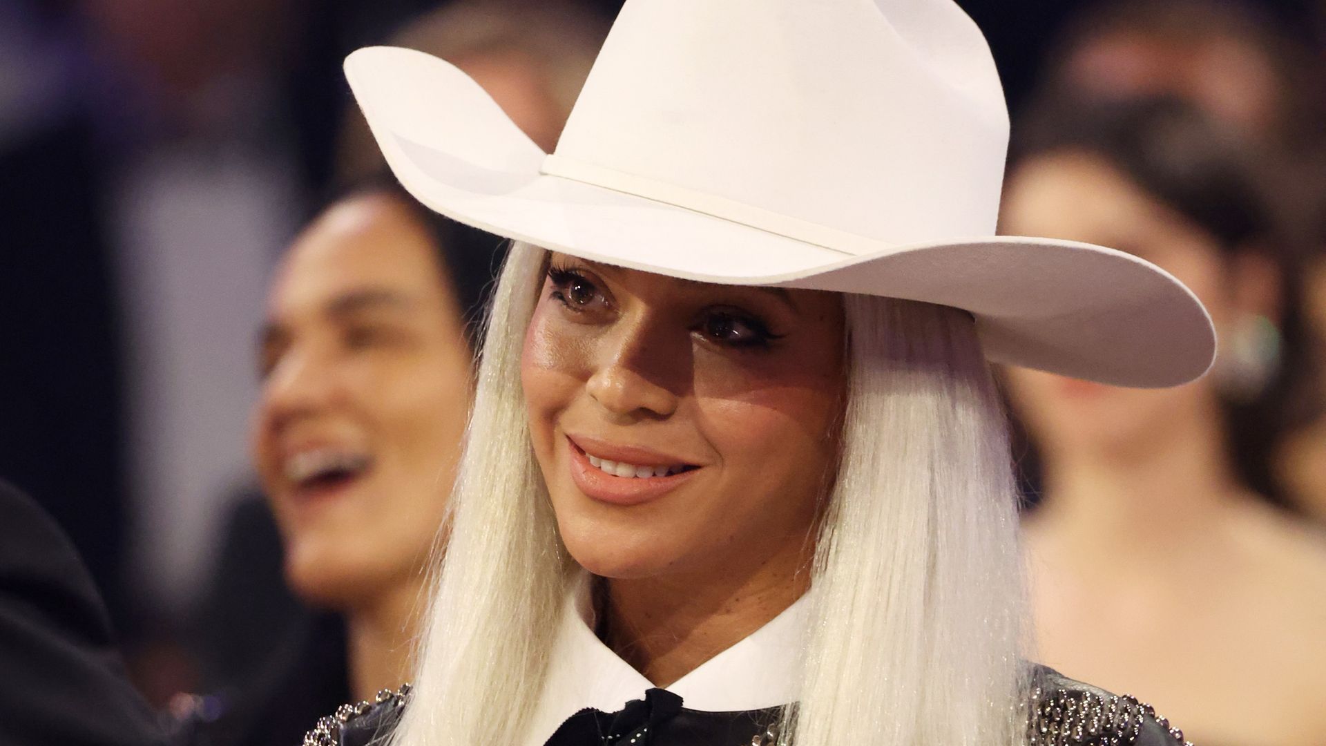 Beyonce wears a white cowboy hat and smiles