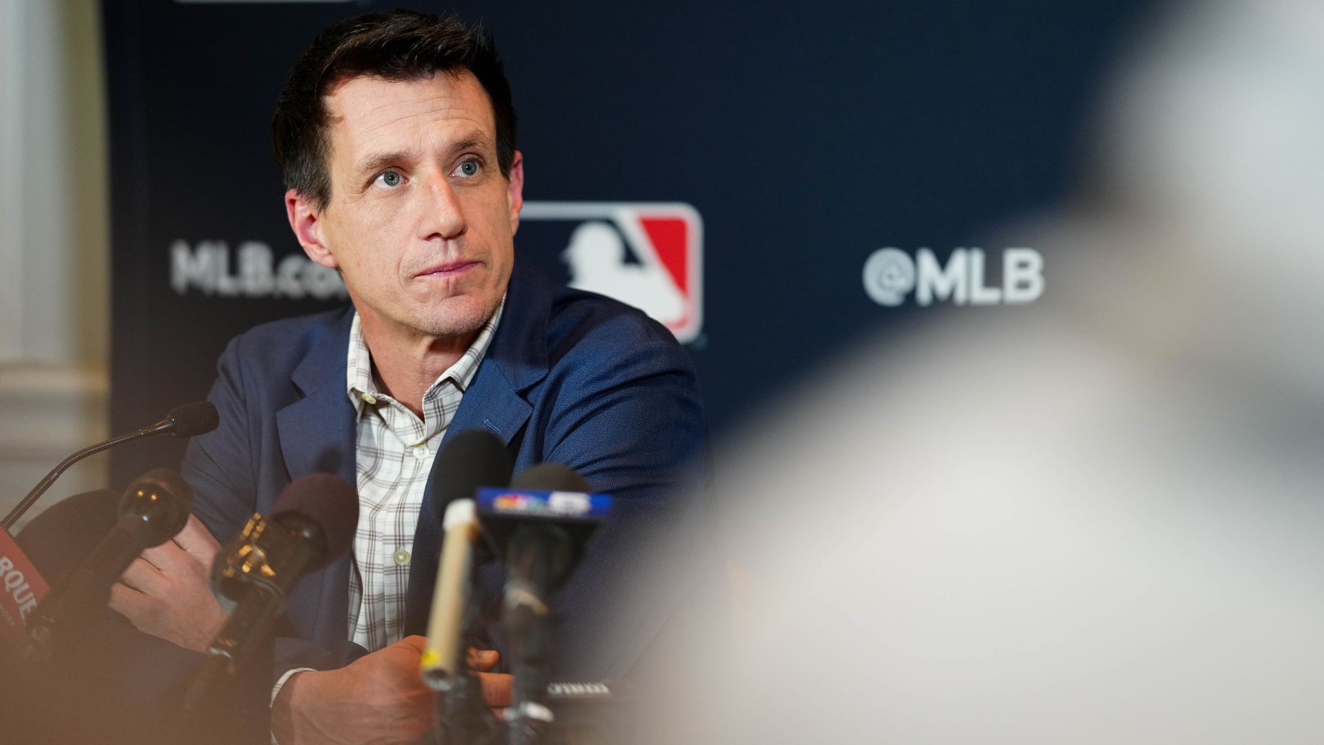 Photo of a man behind a microphone listening to questions