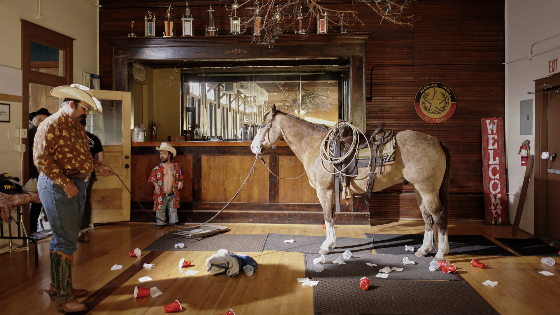 A horse, some cowboys, and many plastic cups in a bar