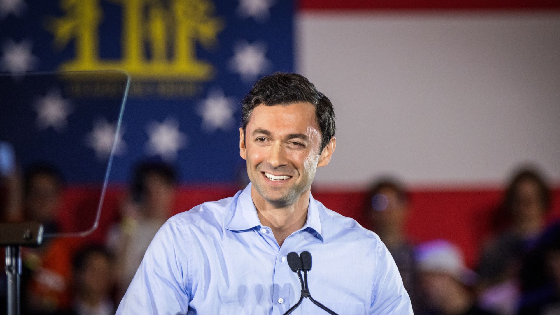 Georgia Se. Jon Ossoff smiles behind a microphone.