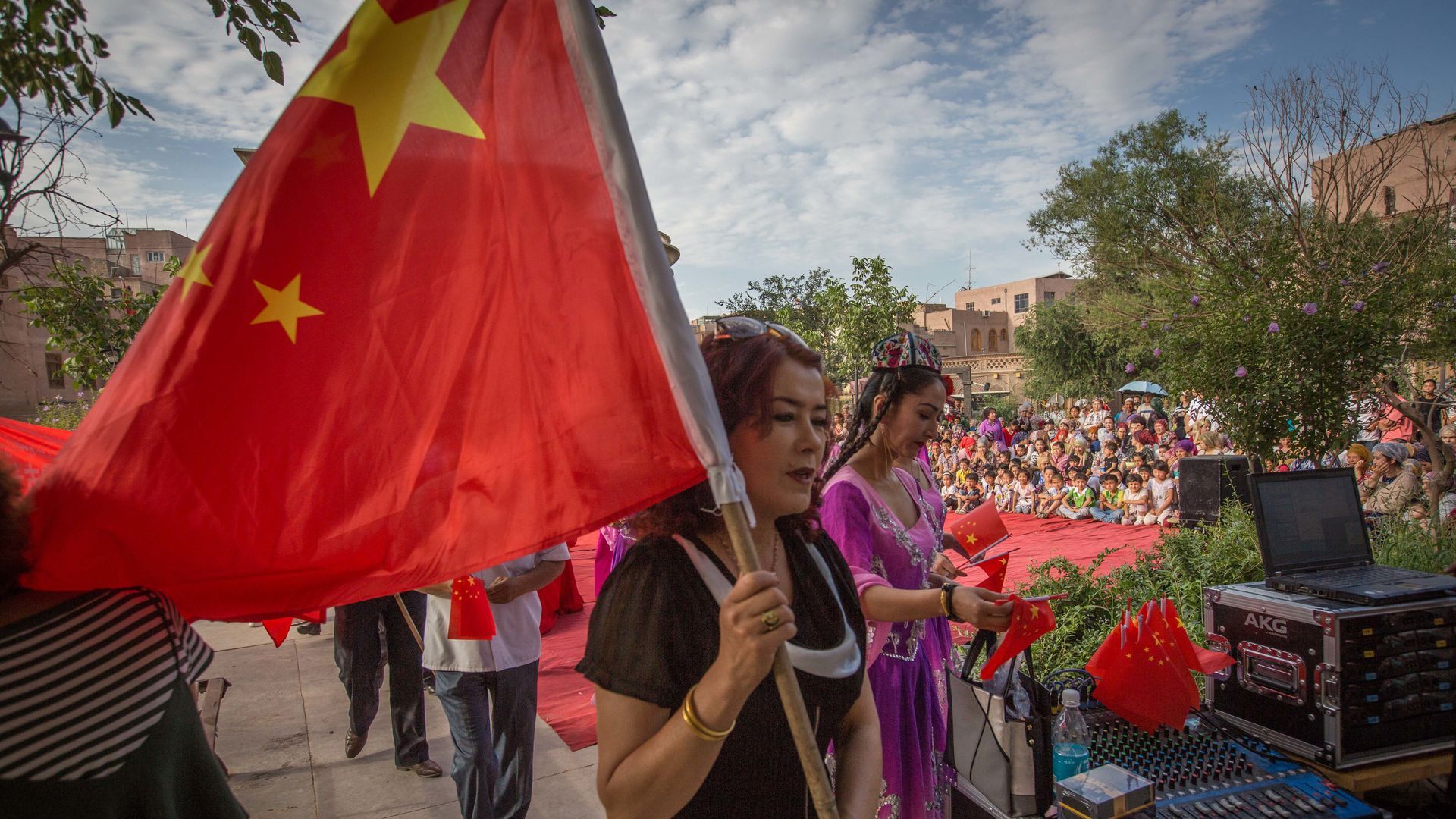 Uighur woman marching, holding a Chinese flag