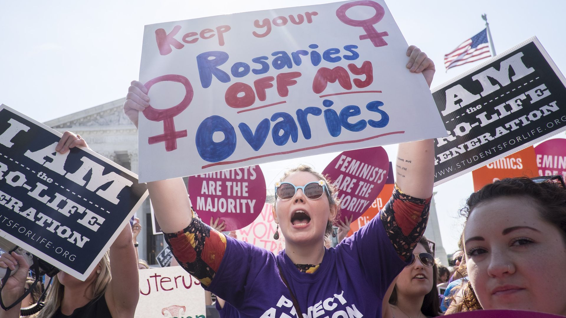 Picture of people in a protest holding signs, some in support of abortion and some against it.
