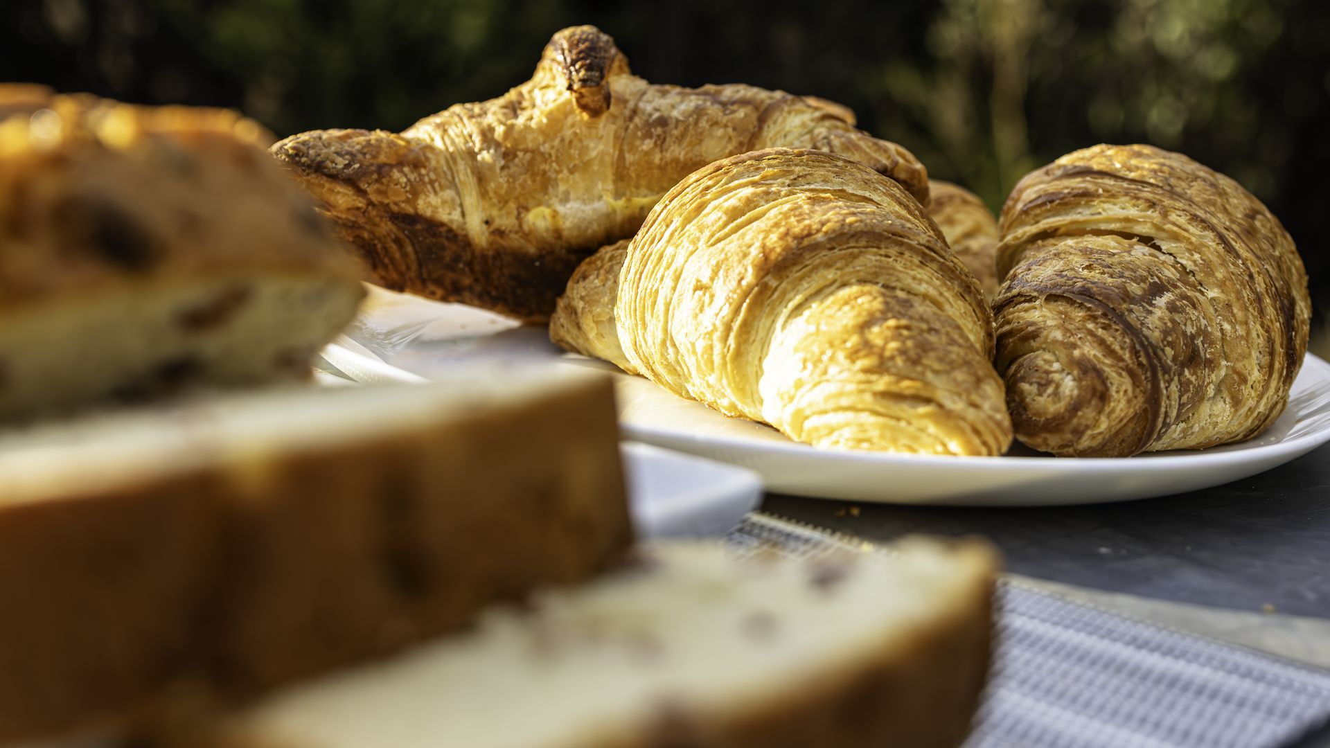 Three croissants in the background with bread slices in the foreground. 