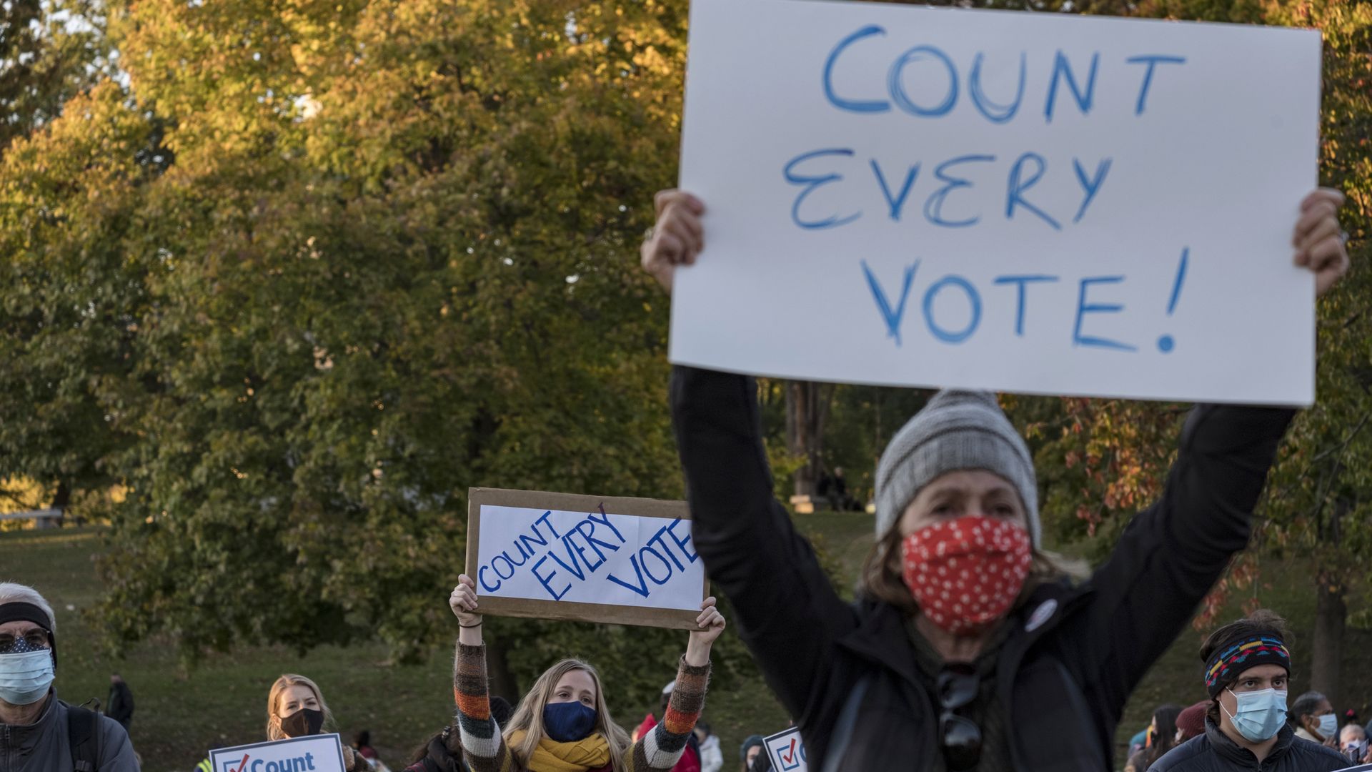 People hold signs that say "count every vote," in Boston.