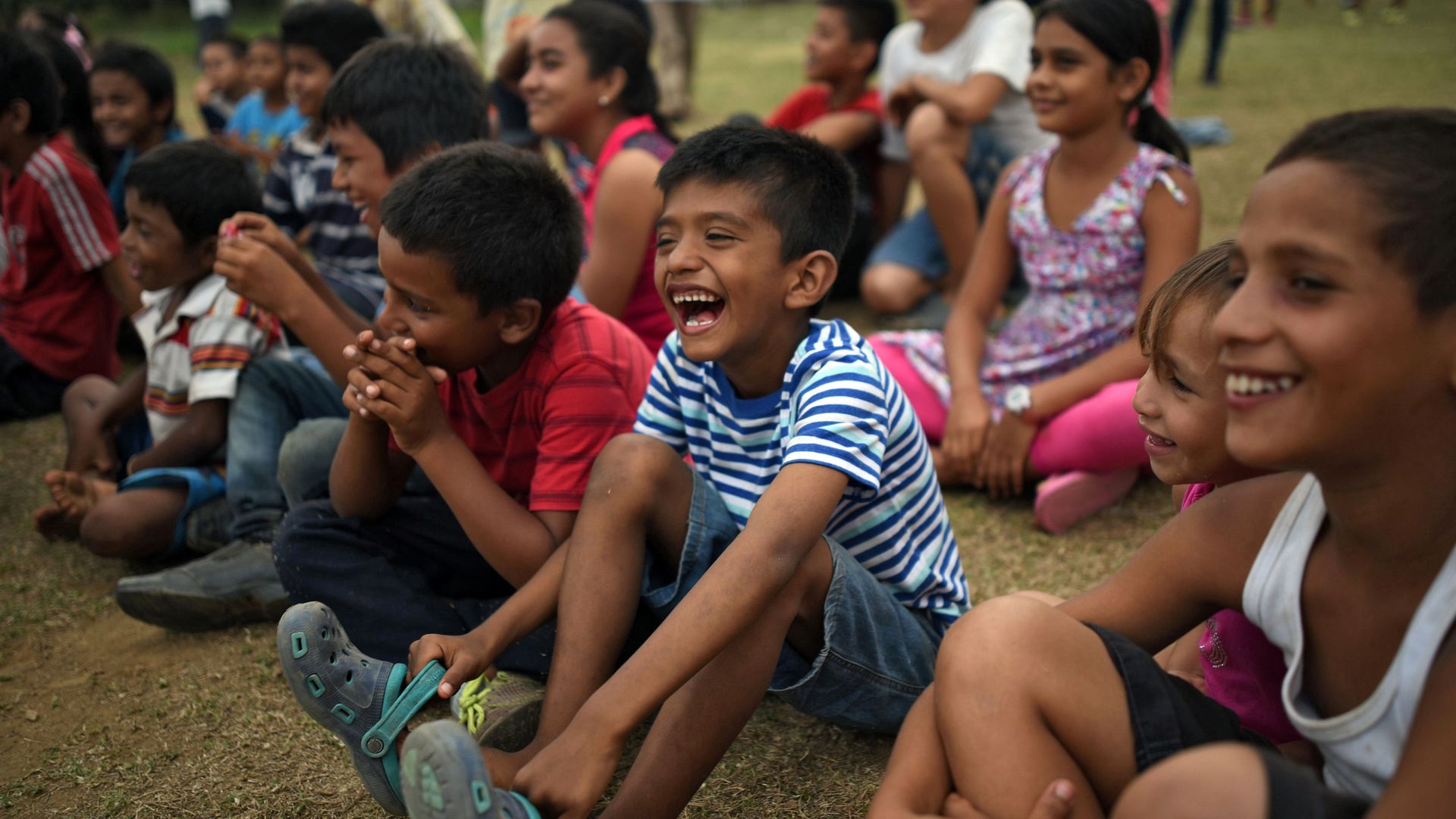 Central American migrant children laugh at a show put on by a clown. 