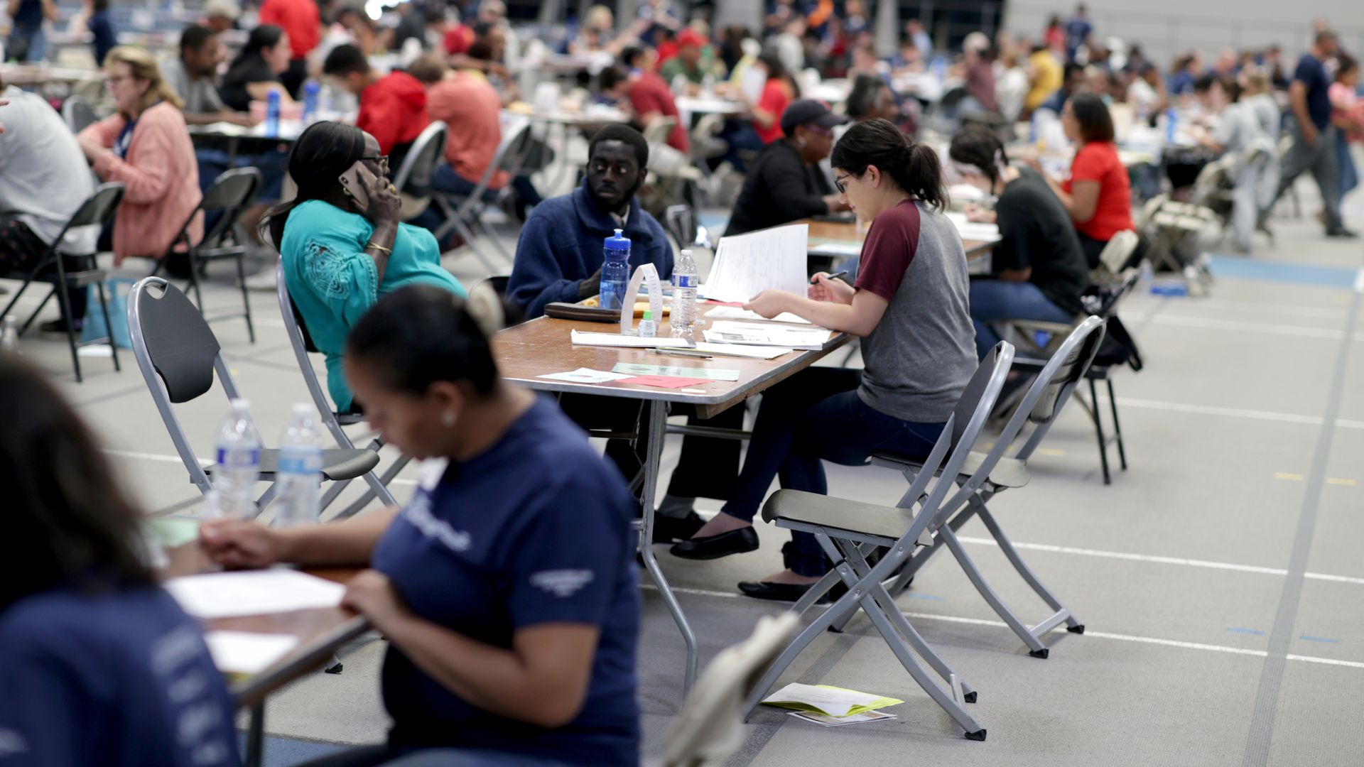 In this image, a row of people in chairs fill out forms.