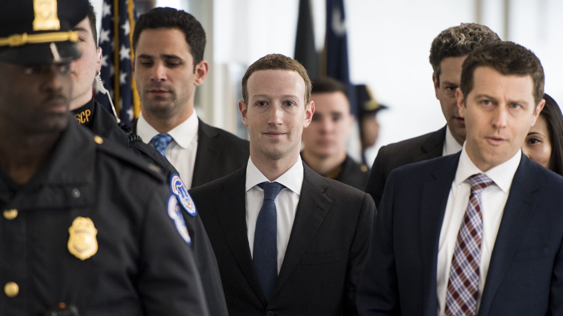Mark Zuckerberg walks surrounded by security, staff and politicos.