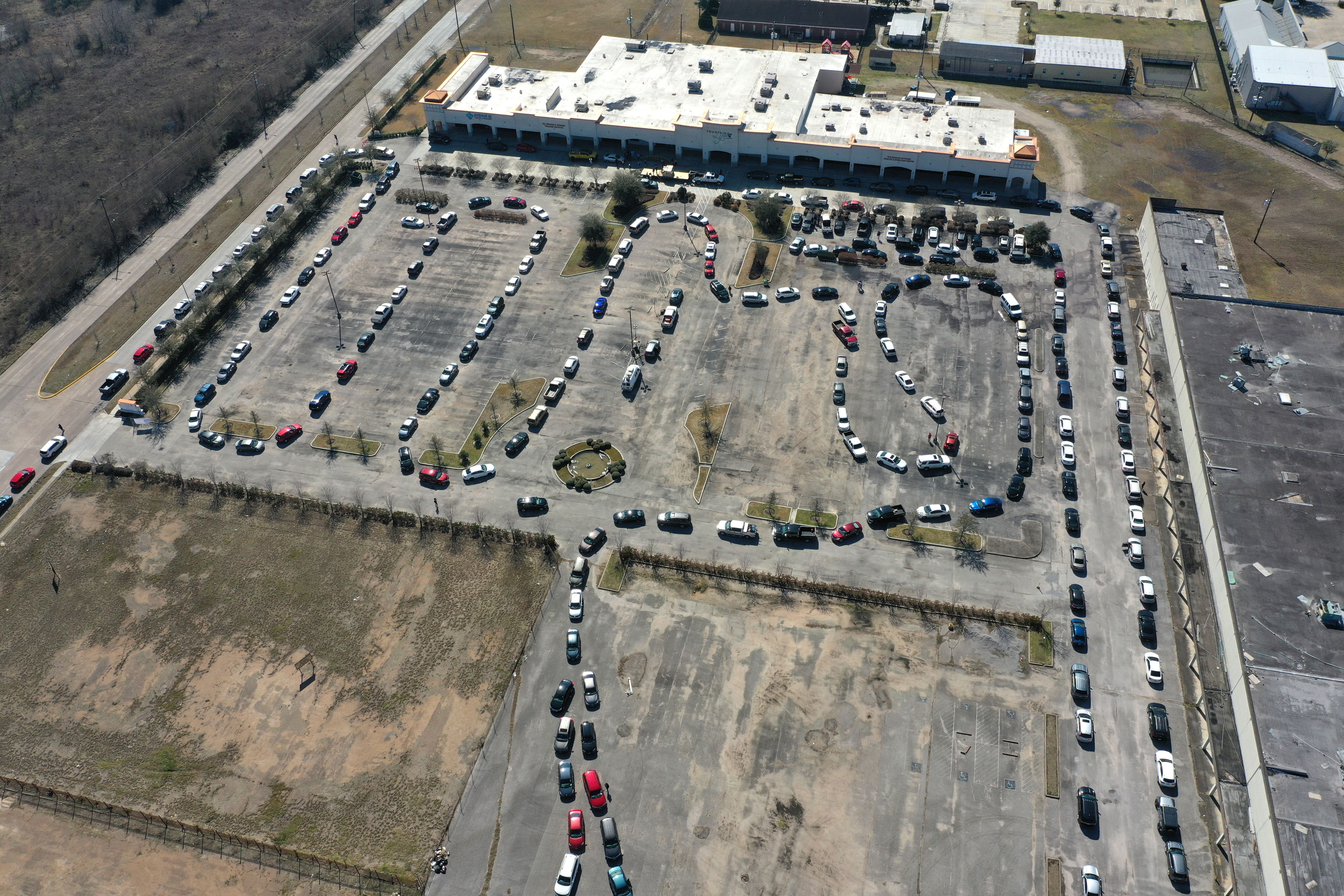 A birds eye view of cars wrapped around a parking lot in a line