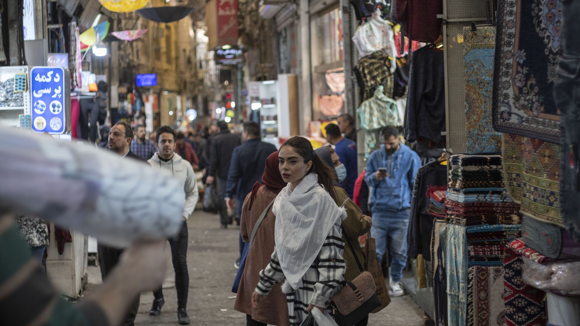 An Iranian young woman looks on as she and her mother walk along an area in Tehran Grand Bazaar 