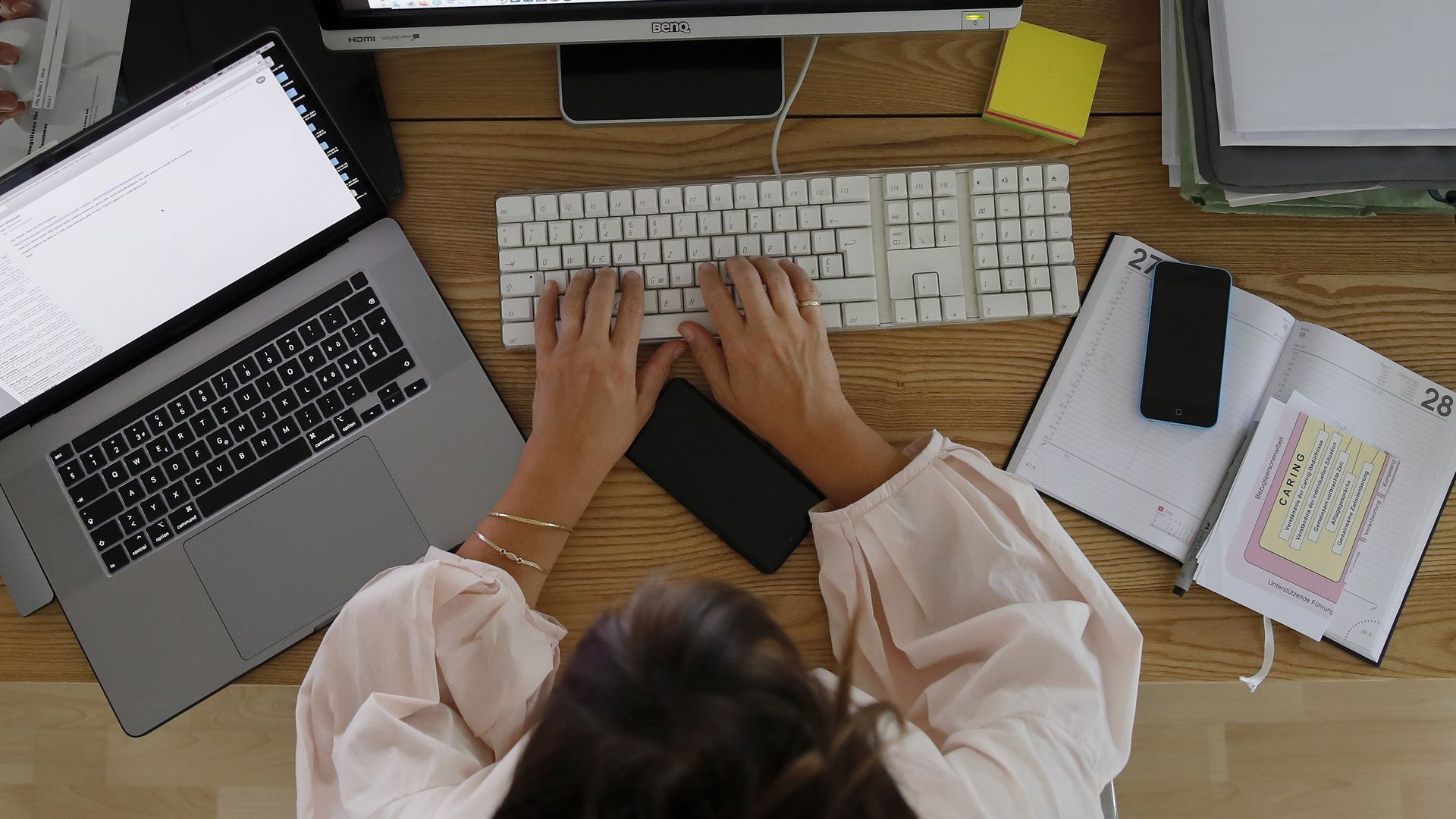 Woman sits at a computer at a work desk.