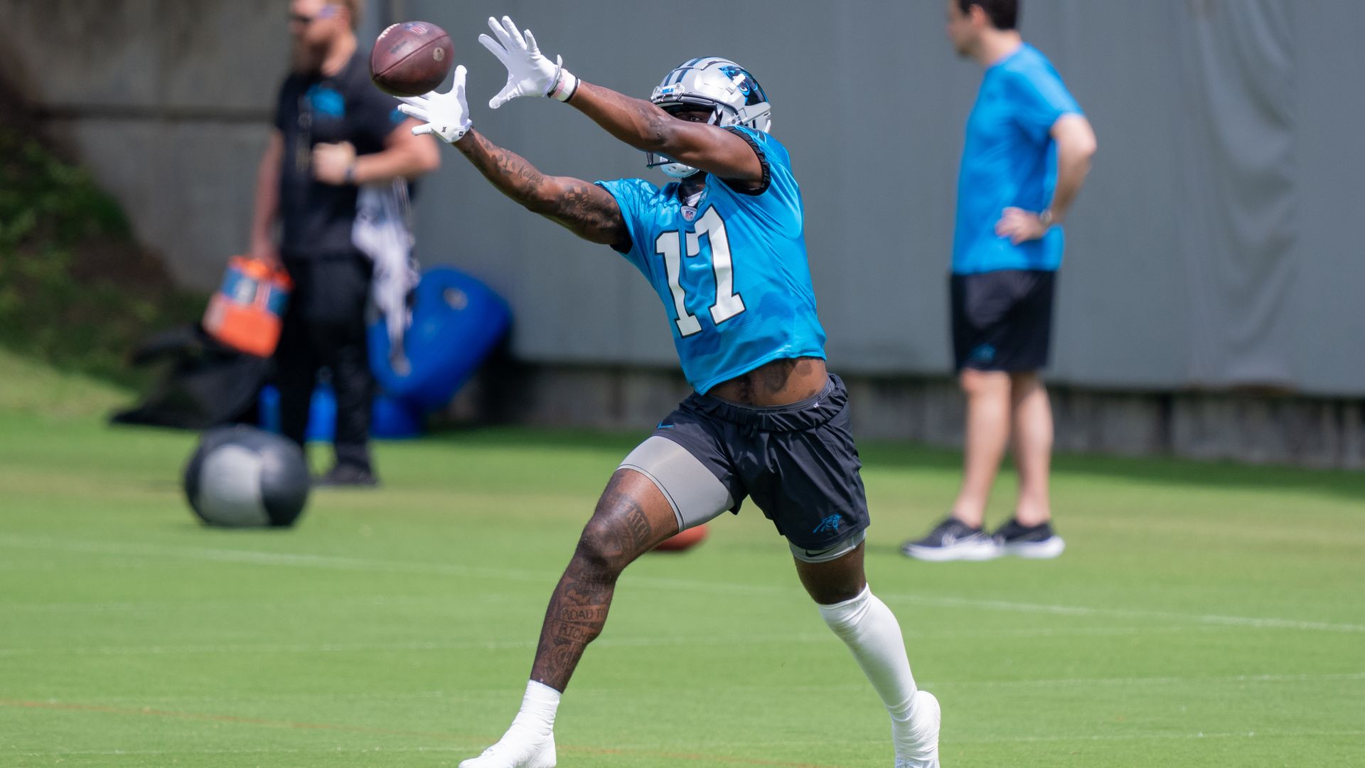 Carolina Panthers player reaches out to catch a football at practice. 