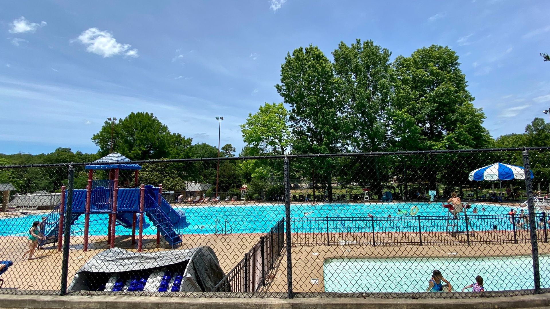 A photo of a public pool filled with kids on a sunny day. 