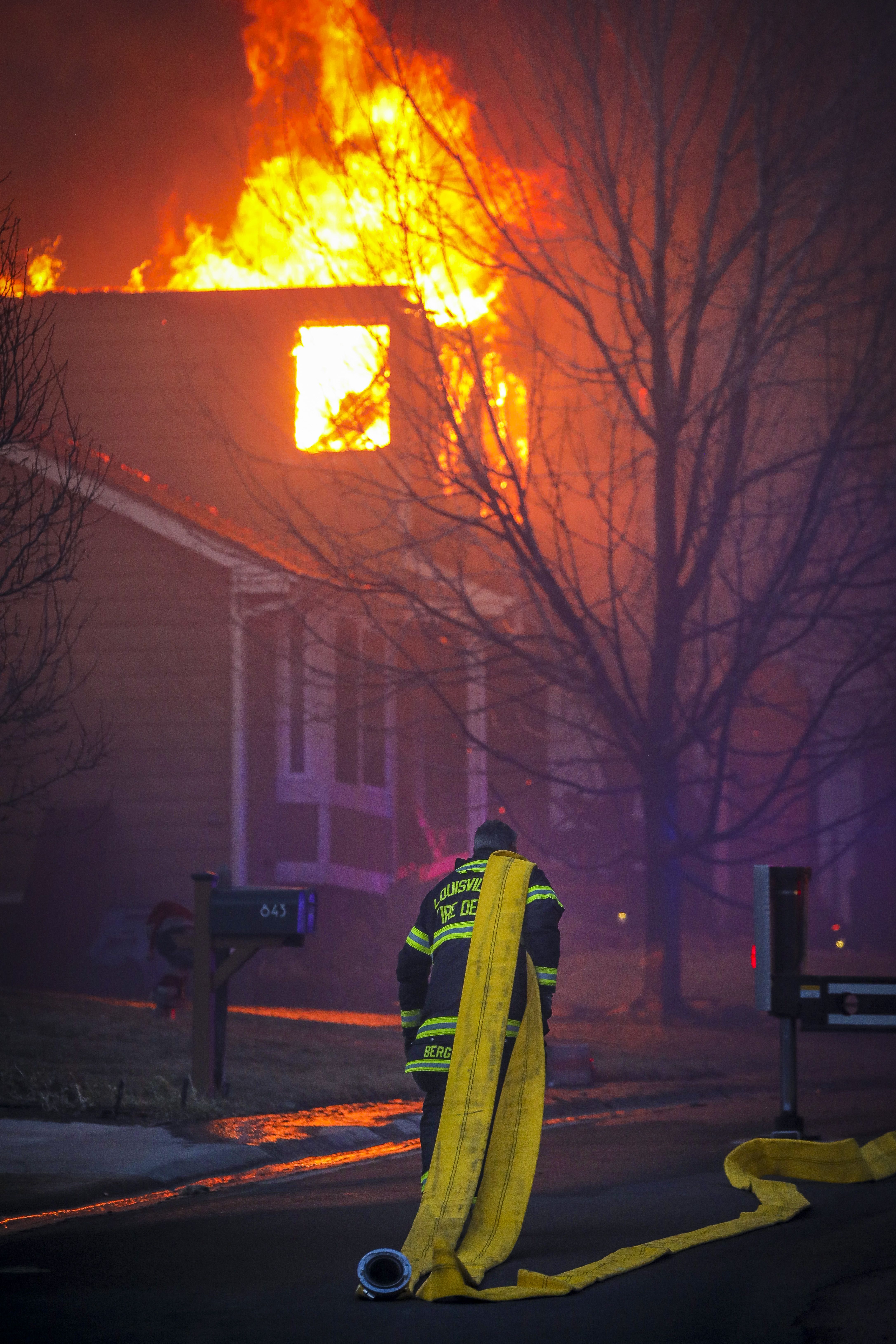 A Louisville firefighter pulls a fire hose through the smoke and haze while fighting a fast moving wildfire that swept through the area in the Centennial Heights neighborhood of Louisville.