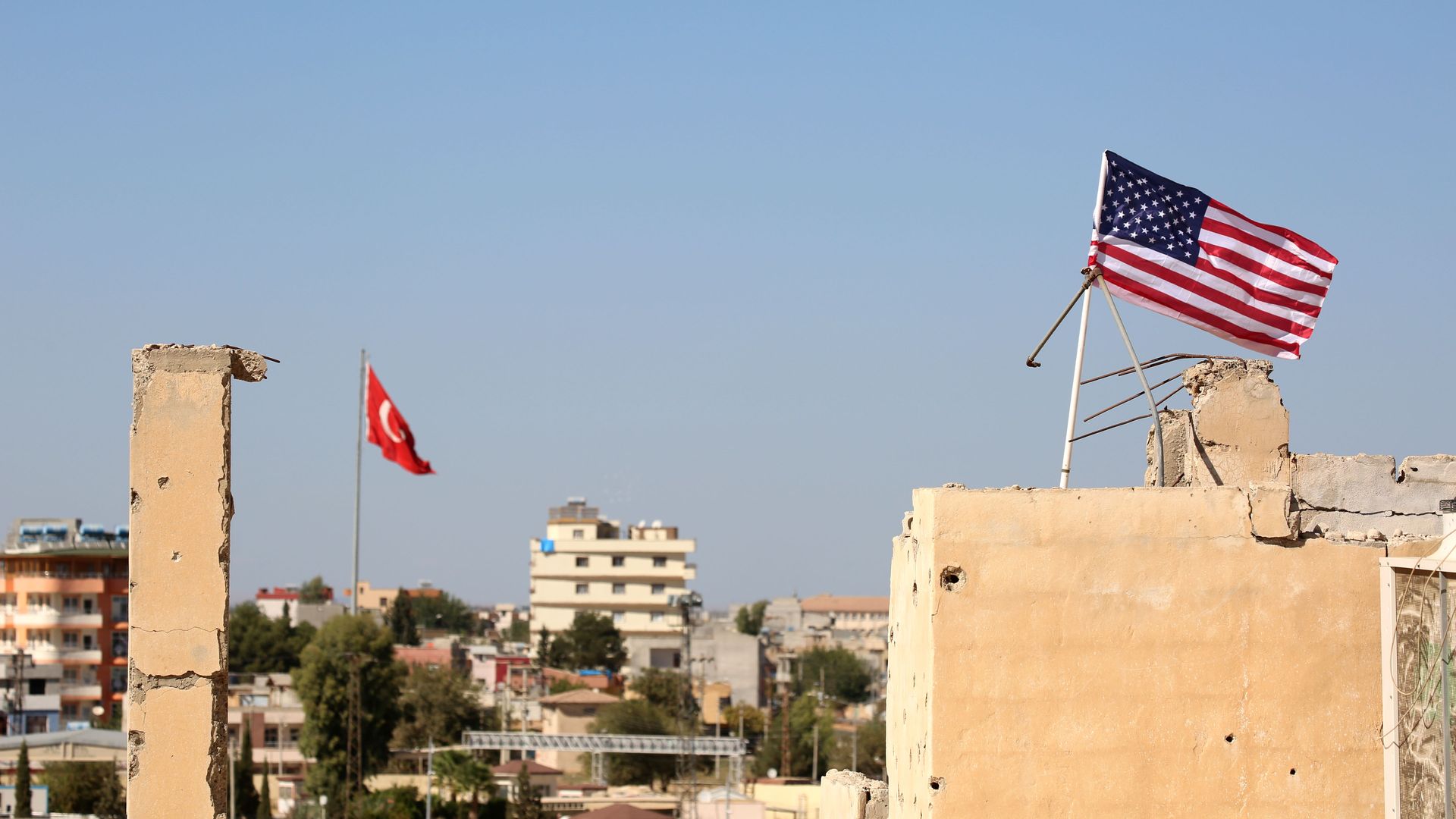 A picture taken on September 17, 2016 shows an American flag (R) fluttering above a building used by the Kurdish police known as the Asayish, in the Syrian town of Tal Abyad.
