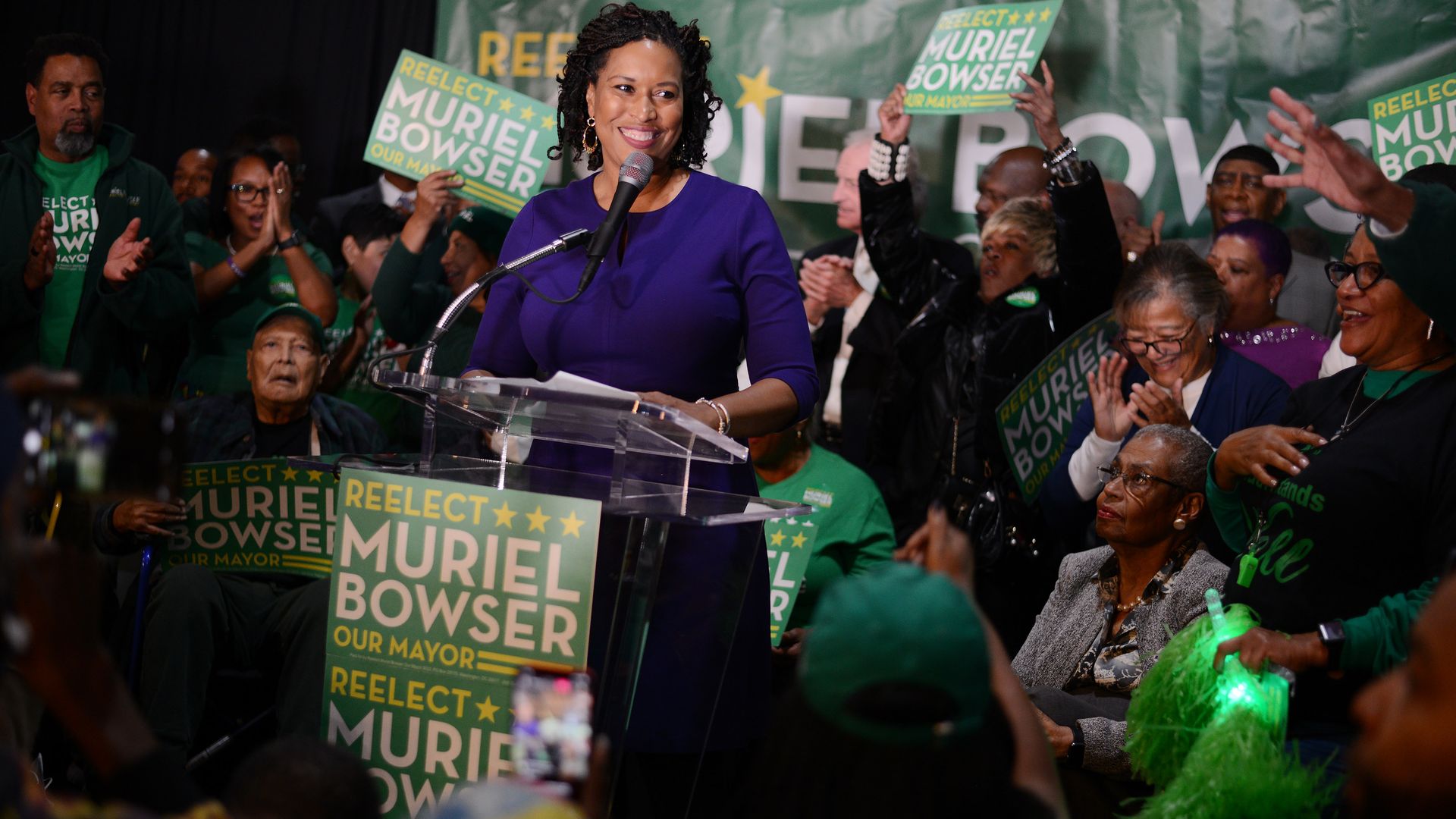 Muriel Bowser speaks at podium surrounded by supporters and family
