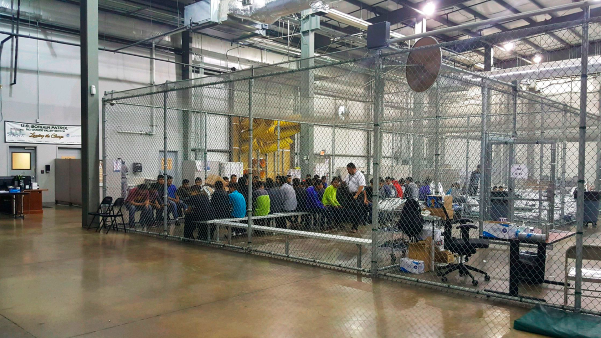 People stand inside a cage made with chain-link fences