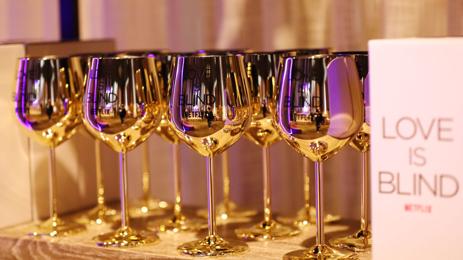 Gold wine glasses next to a sign for Netflix's "Love Is Blind." 