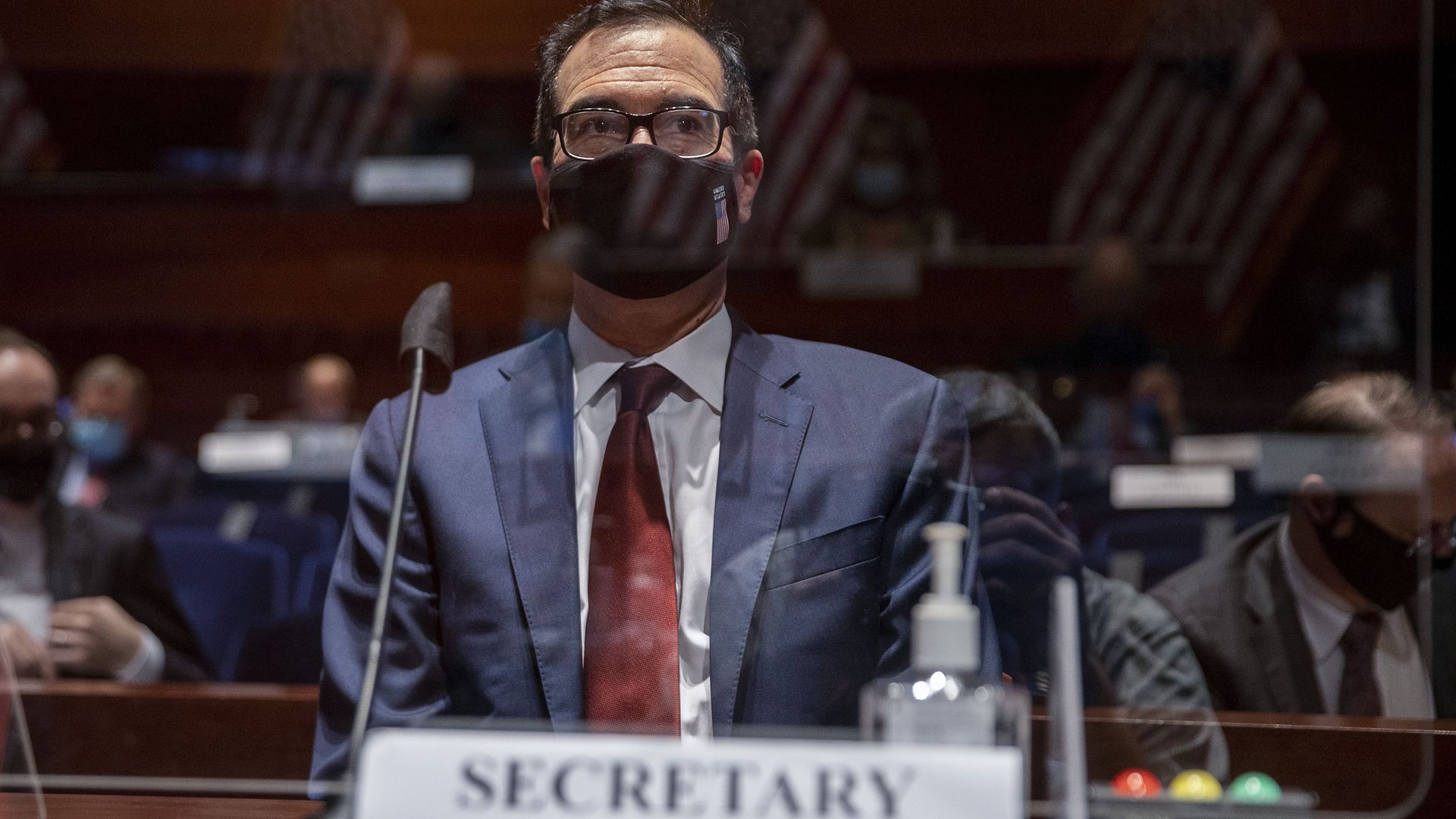 US Secretary of the Treasury Steven Mnuchin wears a mask behind a plexiglass barrier, preparing to testify before the House Financial Services Committee in Washington