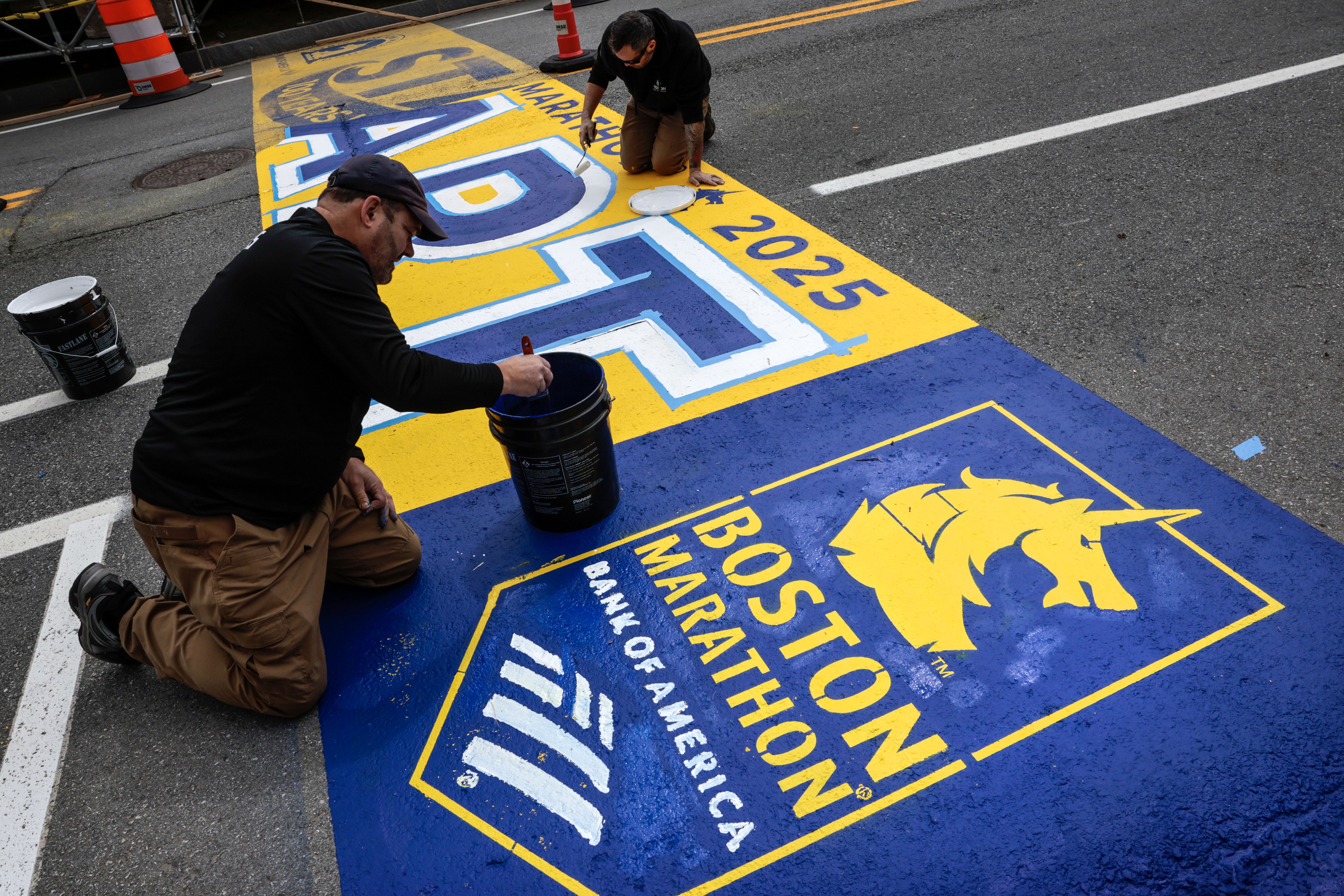 Workers paint the starting line for the 129th Boston Marathon in Hopkinton, Mass.