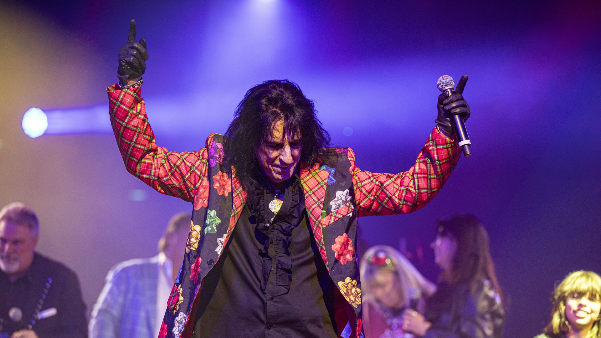 A musician on stage wearing a Christmas suit.