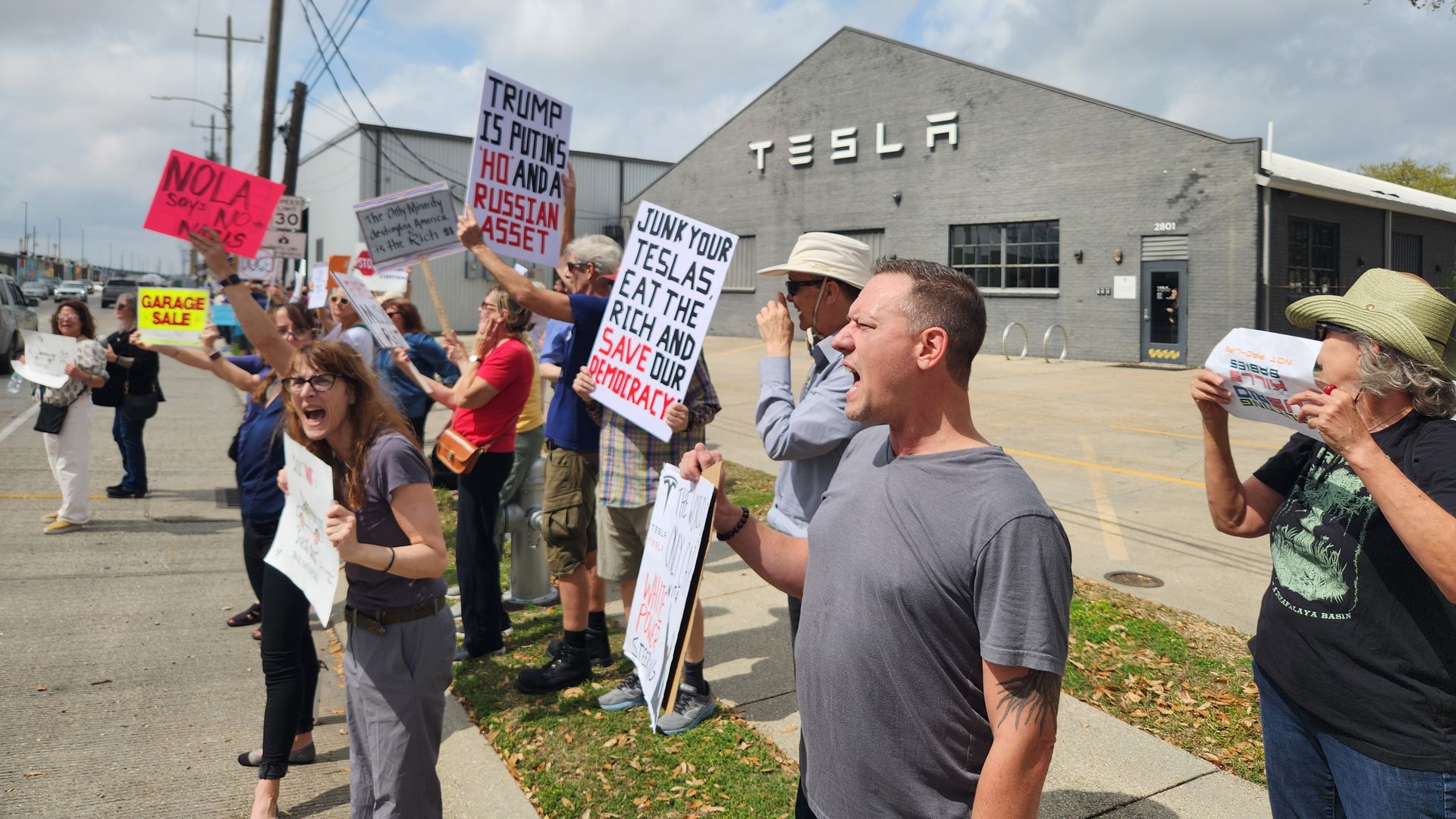 Photo shows people protesting with signs outside a Tesla location in New Orleans.