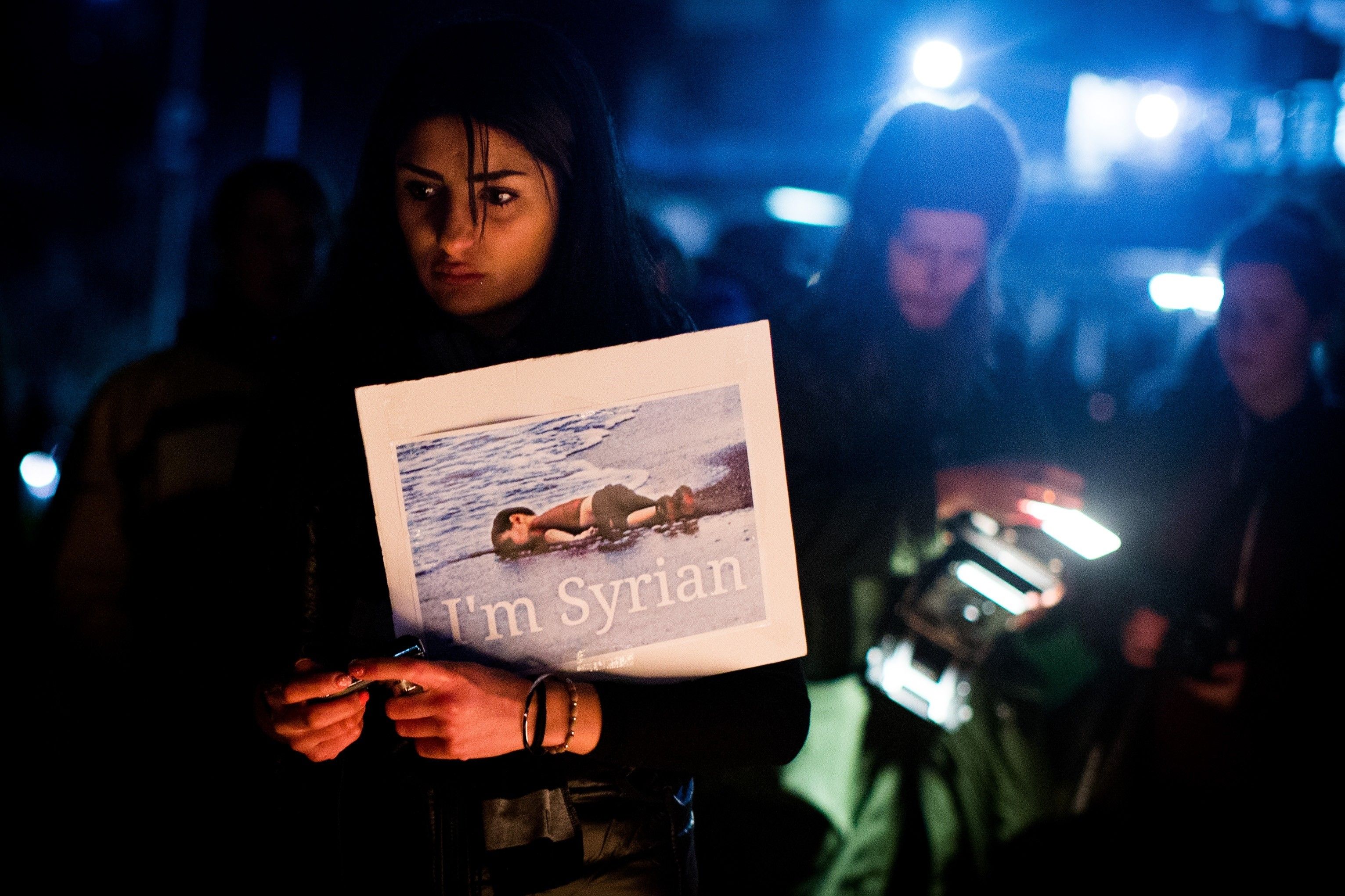 A woman holds a sign during a candle light vigil in honour of Syrian refugee Aylan Kurdi in 2015