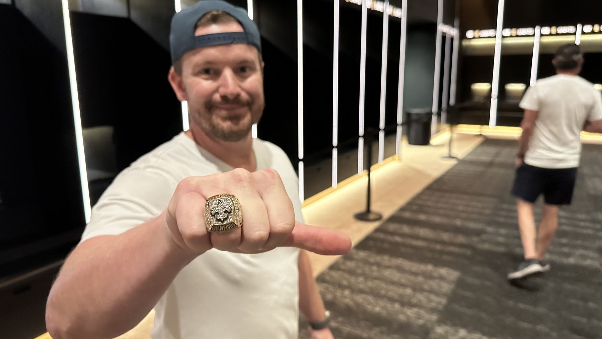 A man shows off his Super Bowl ring as he stands in a locker room.