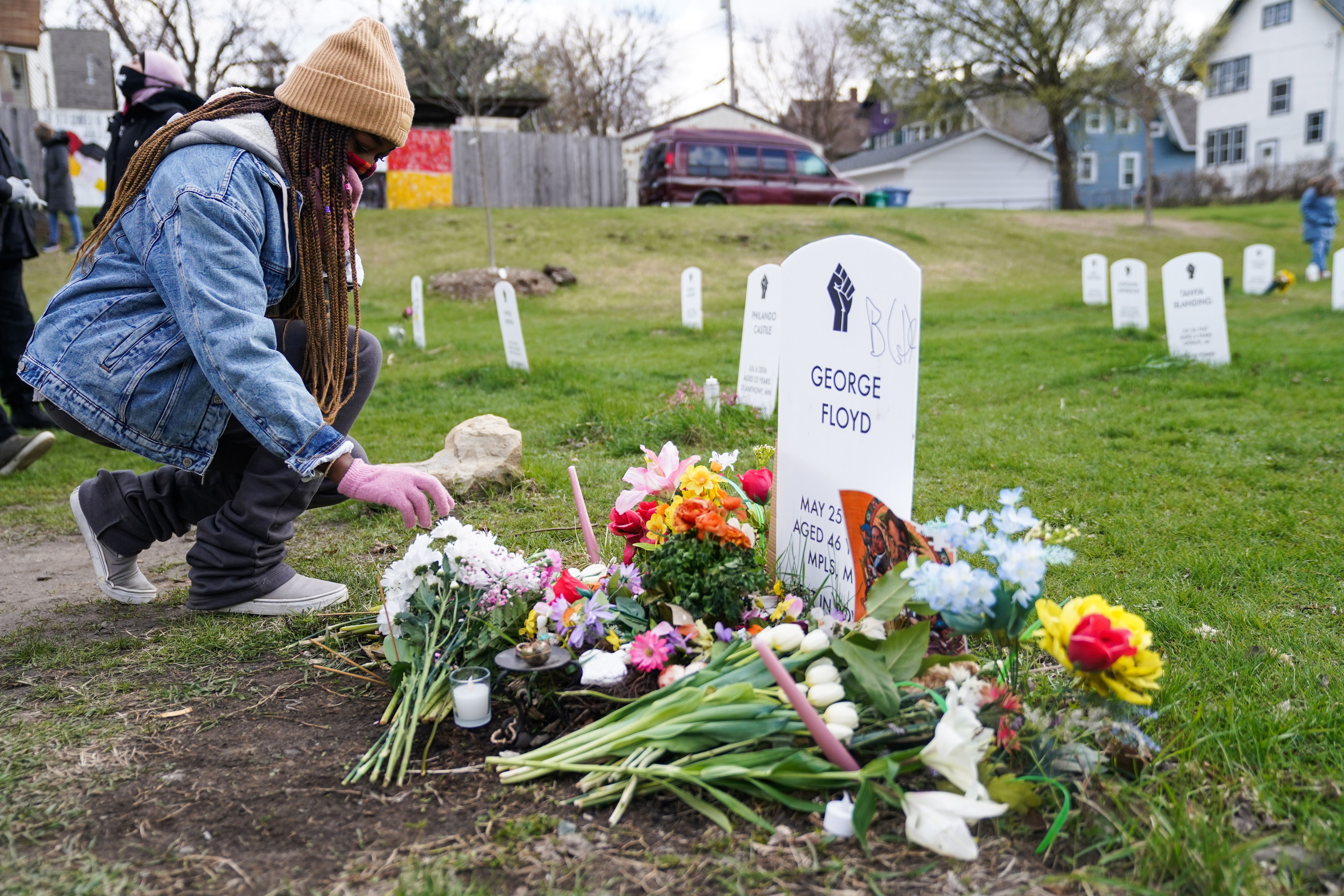 a woman places flowers at the grave of george floyd