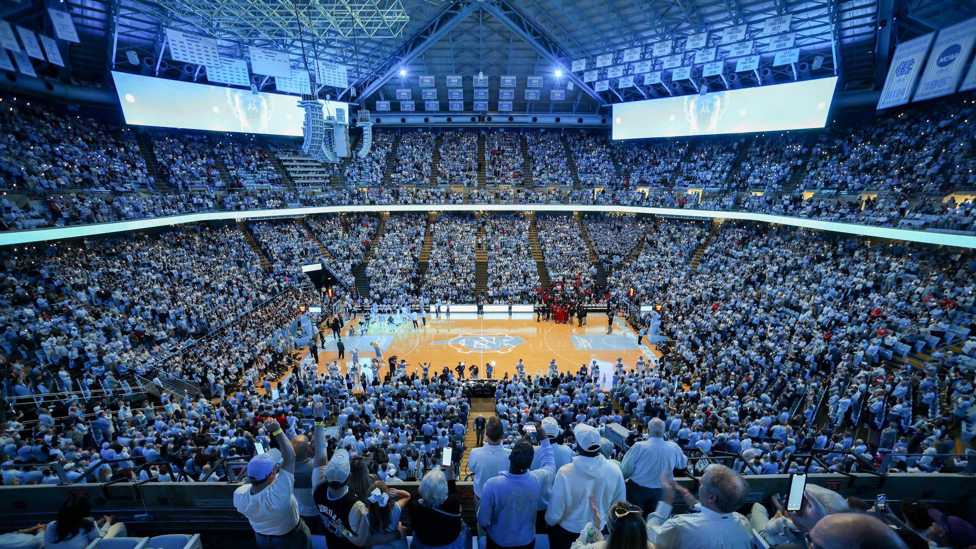 Wide shot of UNC fans packed in Dean Smith Center as the Tar Heels are introduced before a basketball game in 2024.