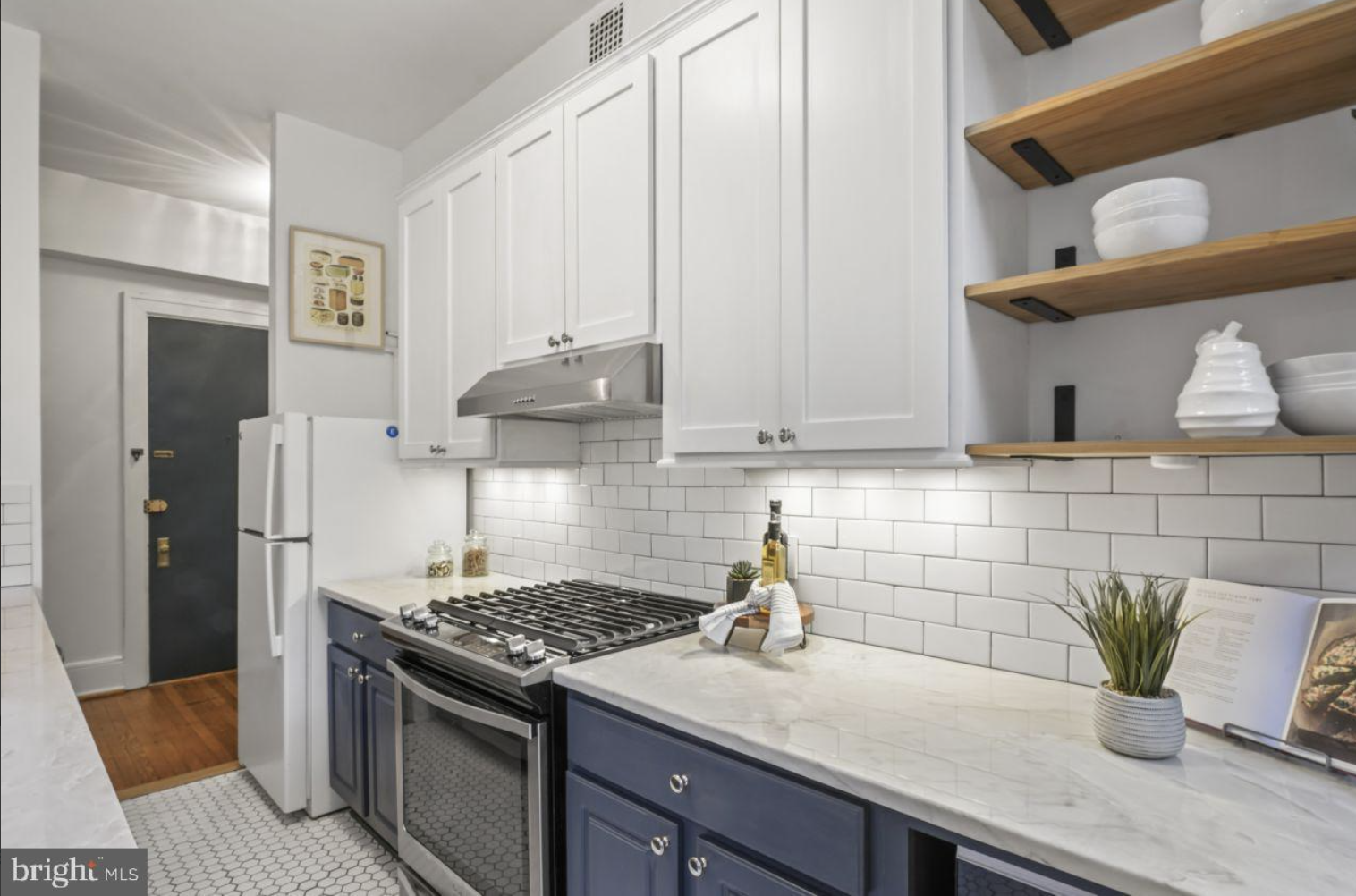 kitchen with navy blue lower cabinets, white upper cabinets and marble counters