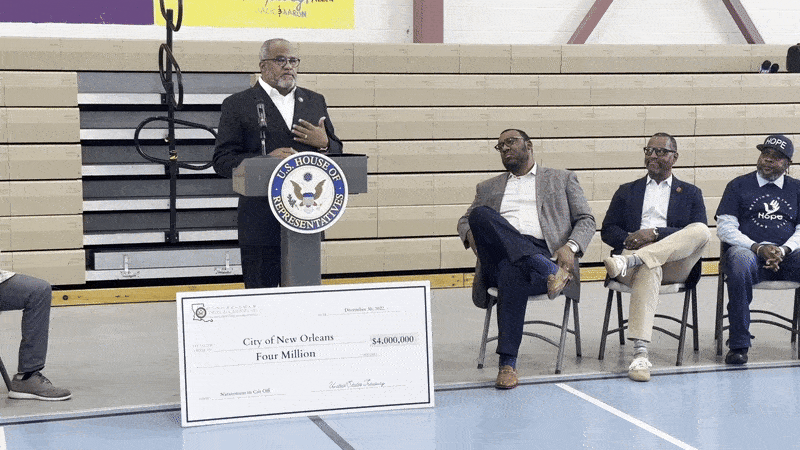 A moving image of Rep. Troy Carter speaking at a podium in a gymnasium.