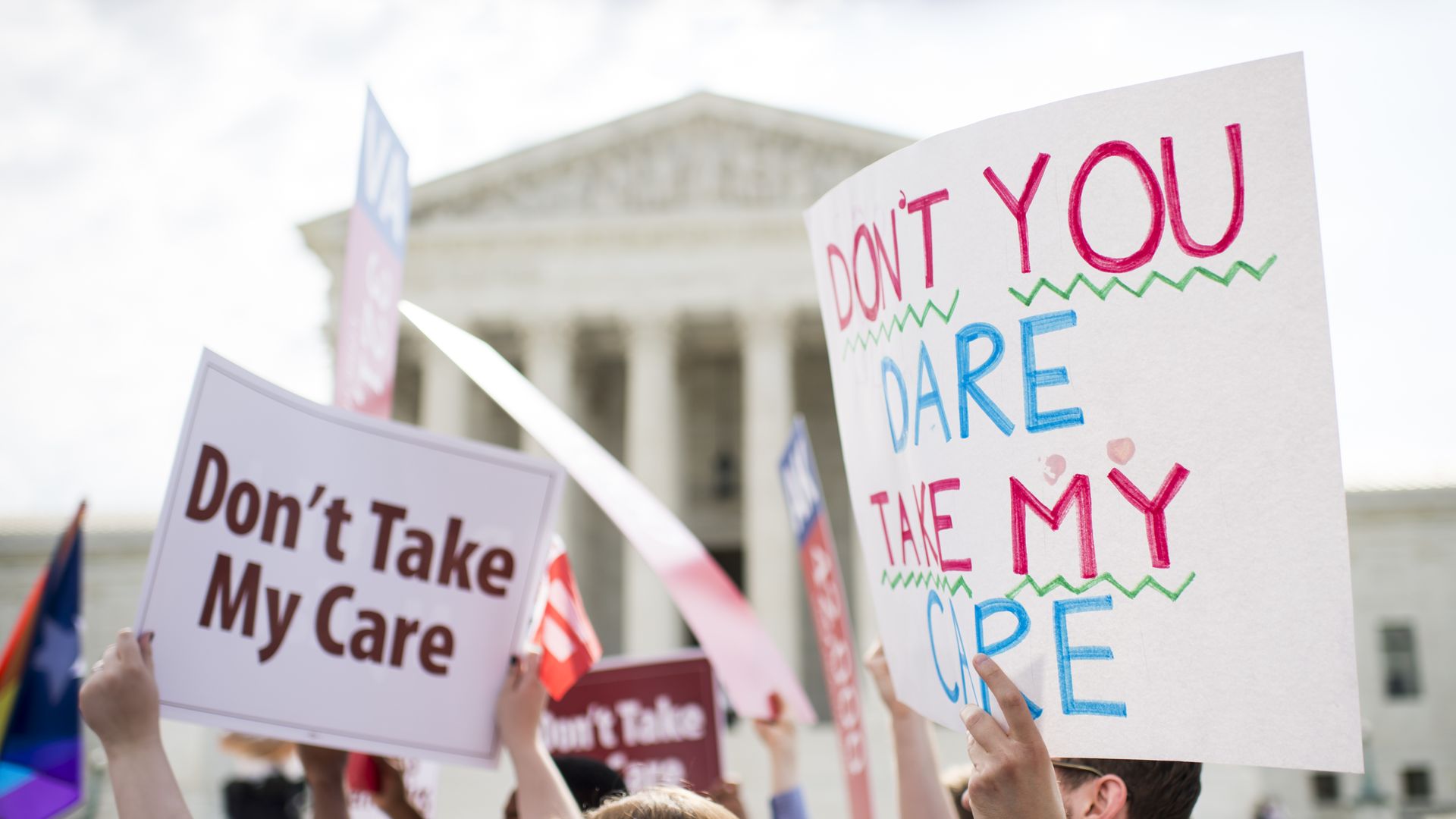 Affordable Care Act supporters hold up signs outside the Supreme Court.