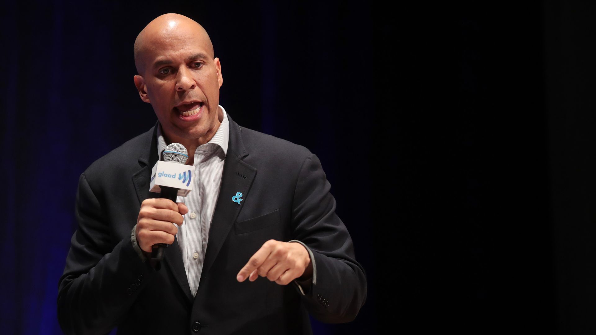 In this image, Booker speaks into a microphone while talking. 