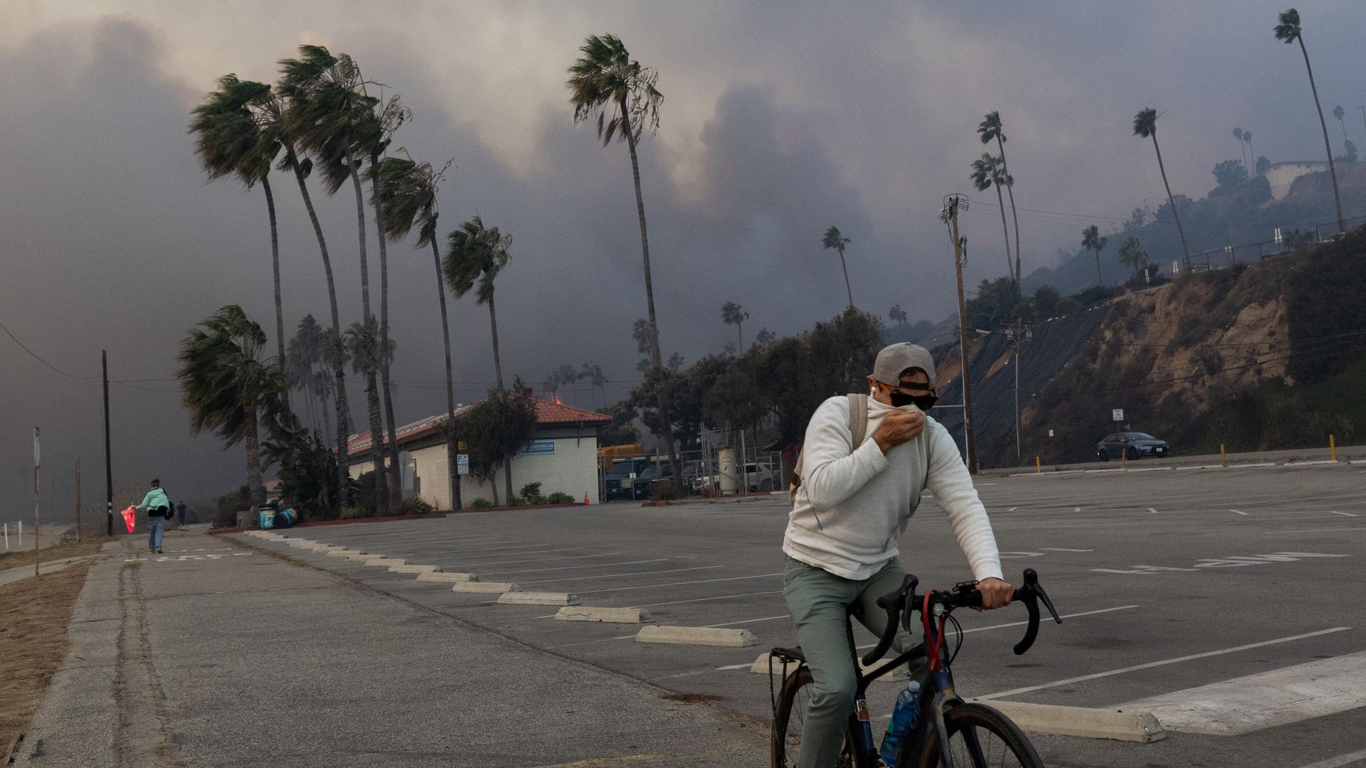  A resident rides through smoke from a brush fire pushed by gusting Santa Ana winds on January 7, 2025 in Pacific Palisades, Los Angeles, California. A fire in the Pacific Palisades area of Los Angeles has forced some residents to evacuate amid "life-threatening and destructive" winds.