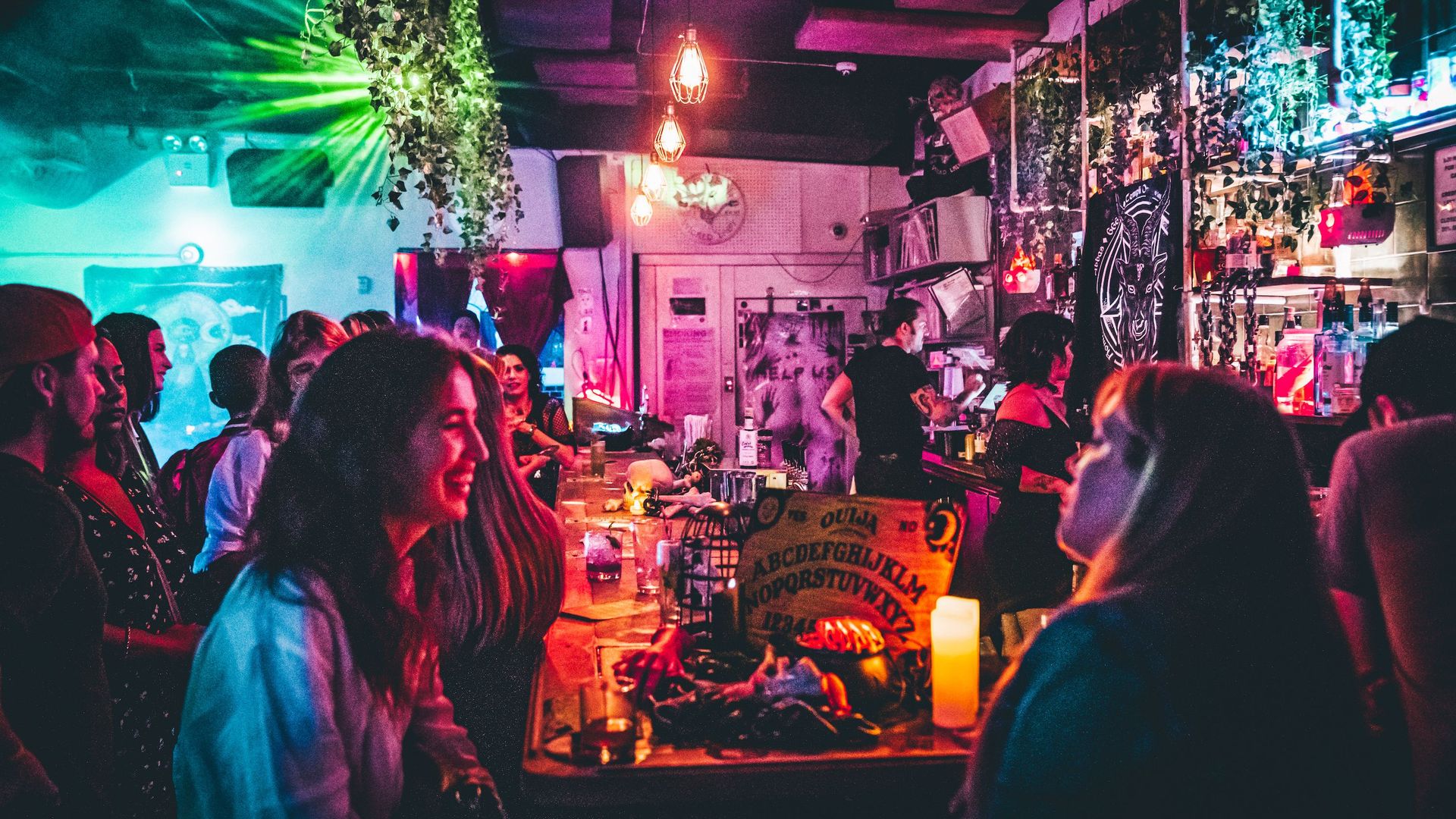 Bar patrons gather around a bar that's decorated for Halloween.