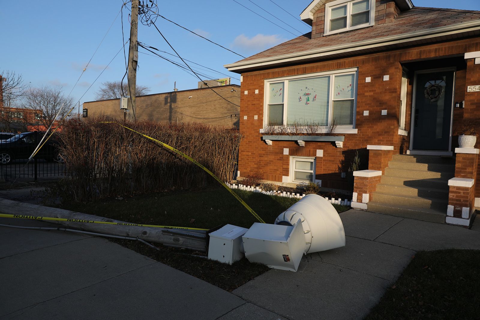 Photo of a utility pole crashed onto the ground in front of a house