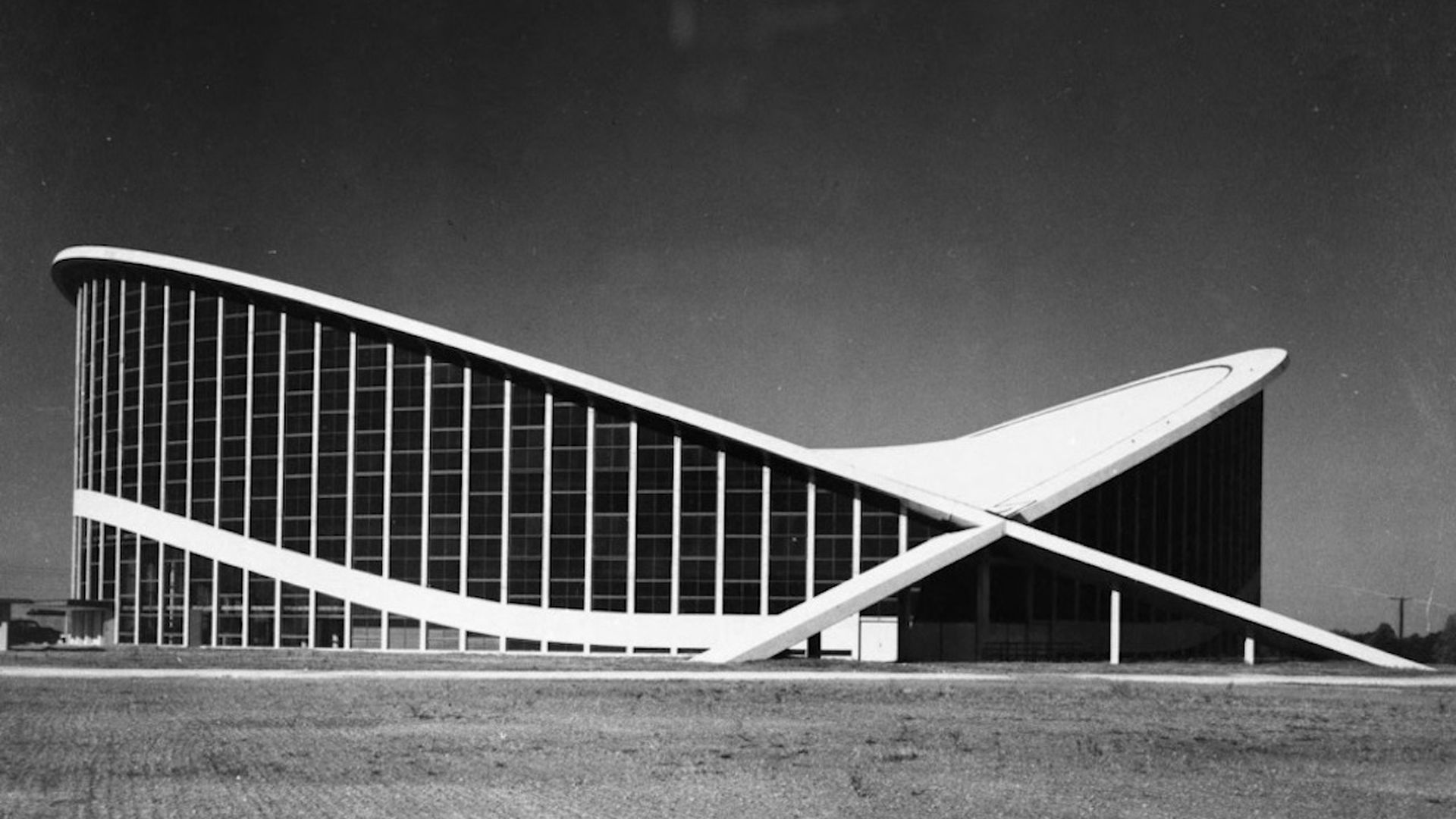 Dorton Arena, with its v-shaped roof, is pictured in black and white. 