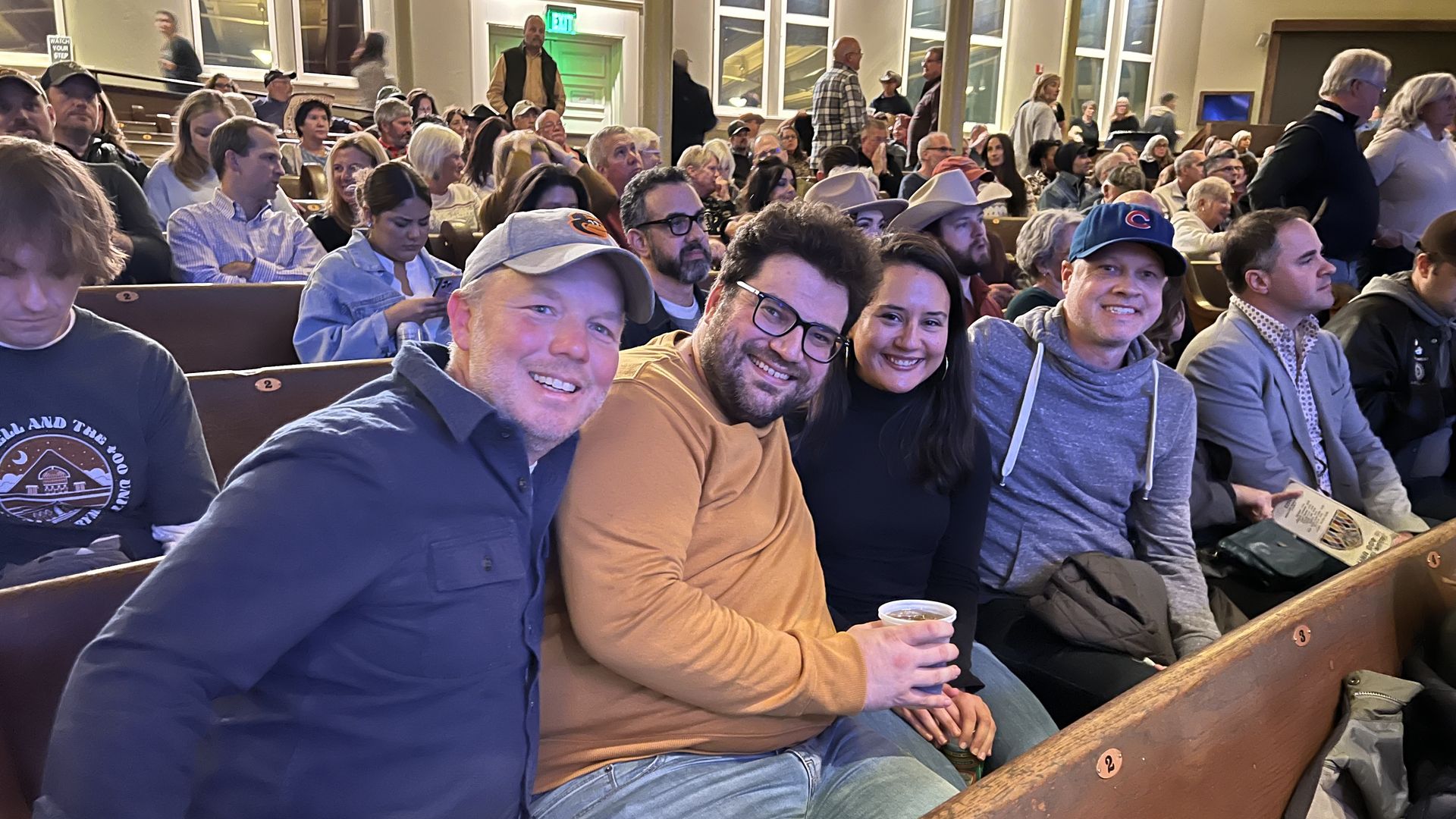 A group of people smiling in a pew at a concert hall.