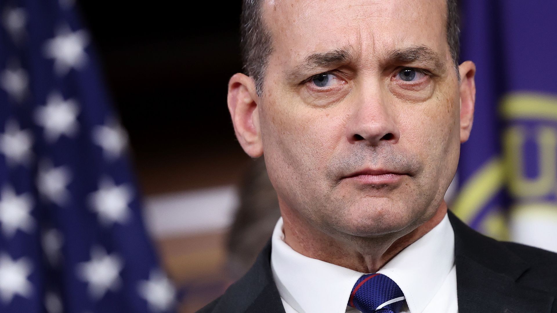 Rep. Bob Good, wearing a black suit and standing in front of an American flag and a House of Representatives flag.