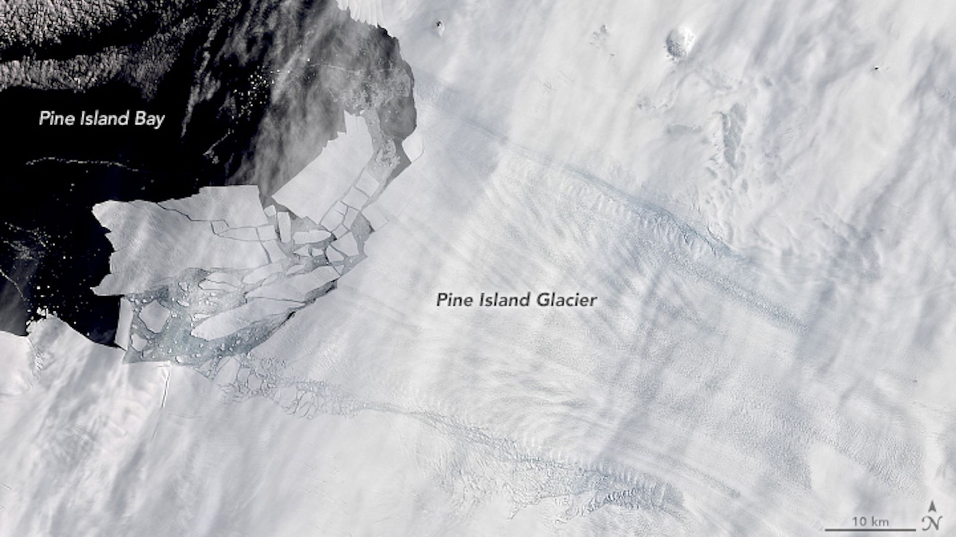 Satellite view of ice in Antarctica with icebergs drifting into the sea.