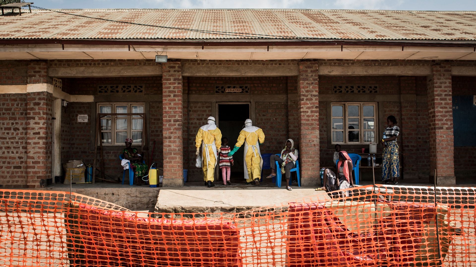 Photo of child, who's suspected of being infected with Ebola, being led by the hand into a building in DRC