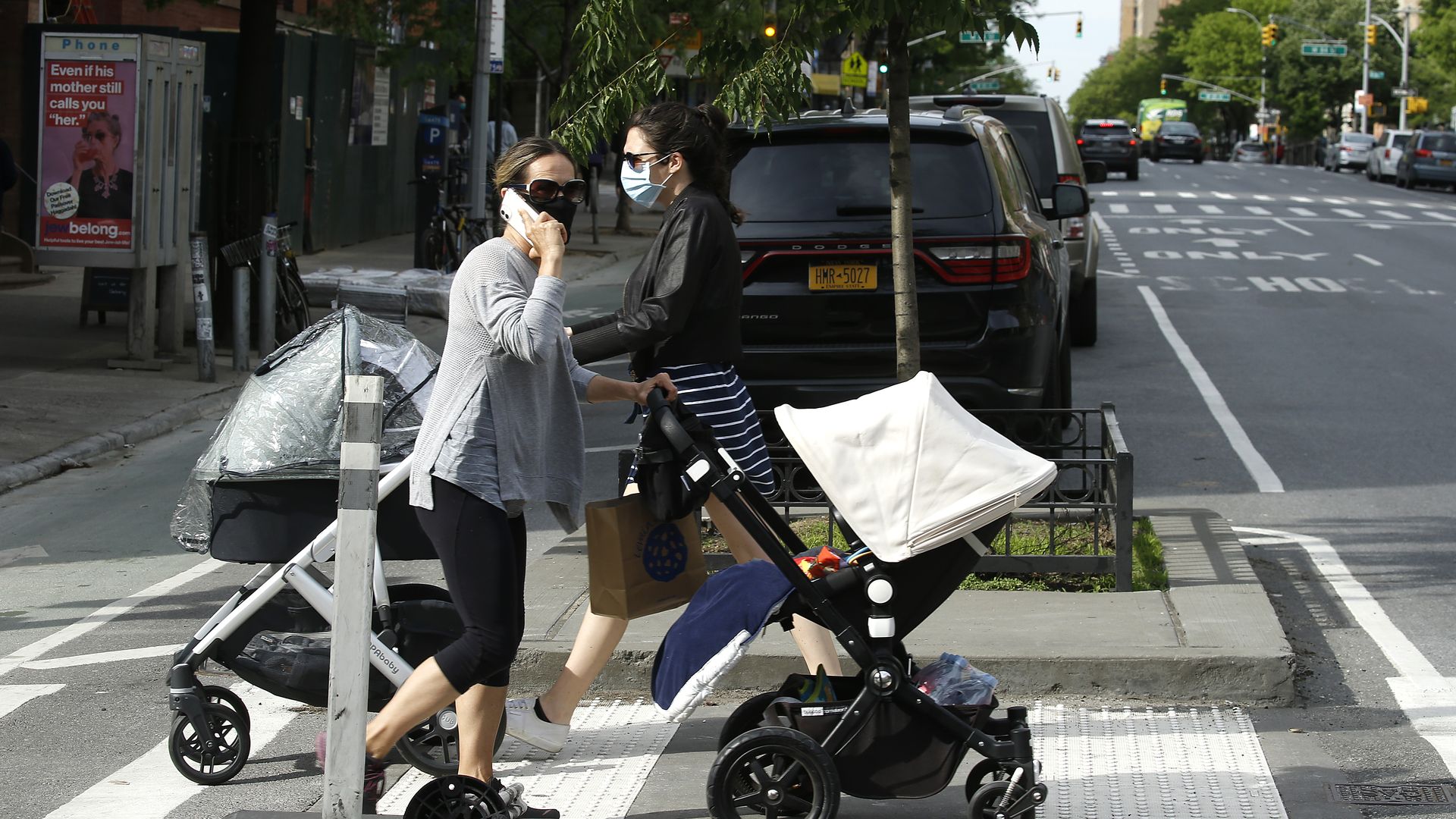 Two people wearing face masks pushing strollers in New York City.