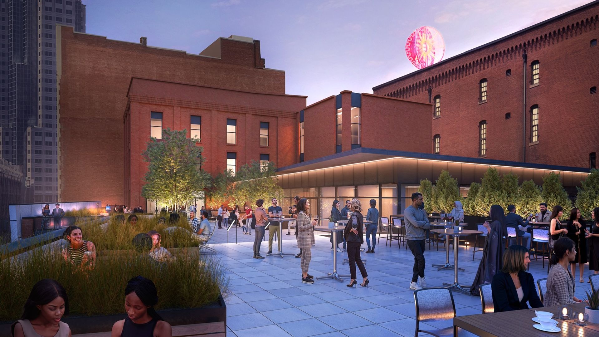 People mingle on a rooftop terrace at dusk amid brick buildings, planters and trees; modern glass walls frame the space as a pink-lit circular amusement ride rises behind.