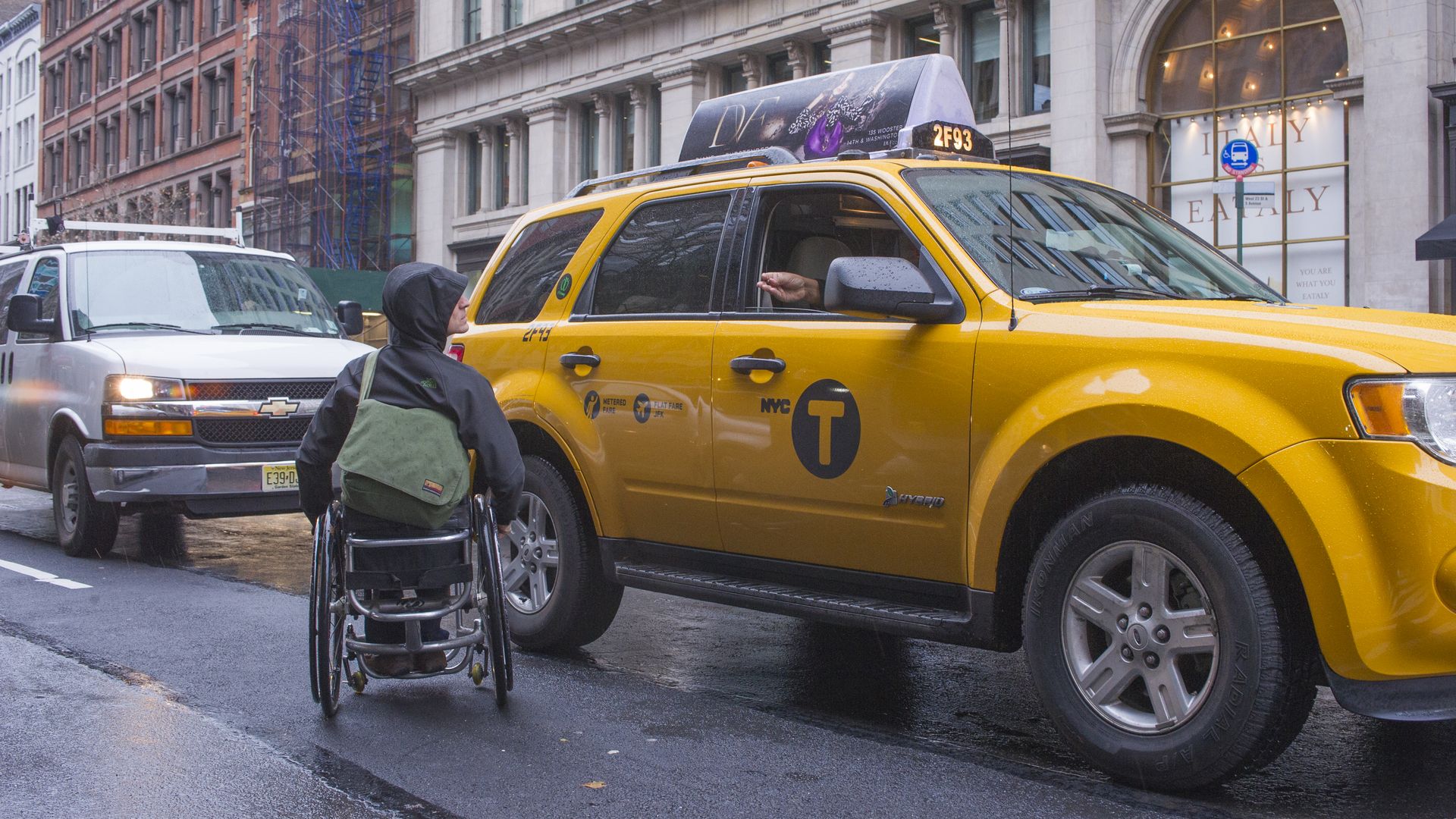 A man in a wheelchair hails a taxi