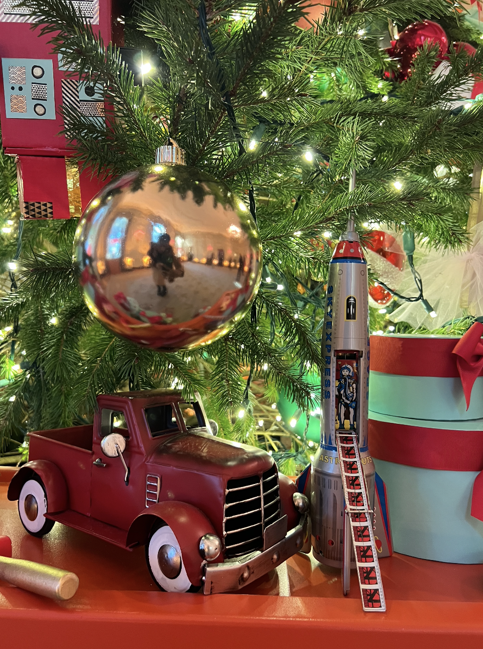 A close up of Christmas tree decorations including a spaceship and a truck.