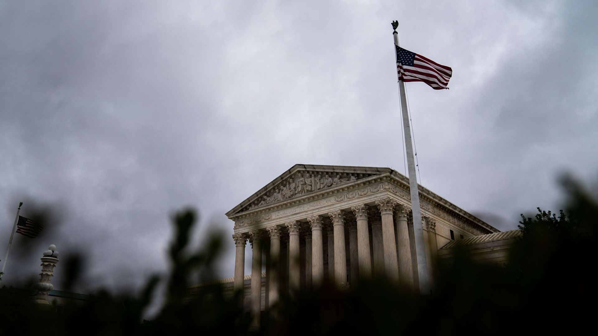 Photo of the Supreme Court building and an American flag flying on a pole next to it