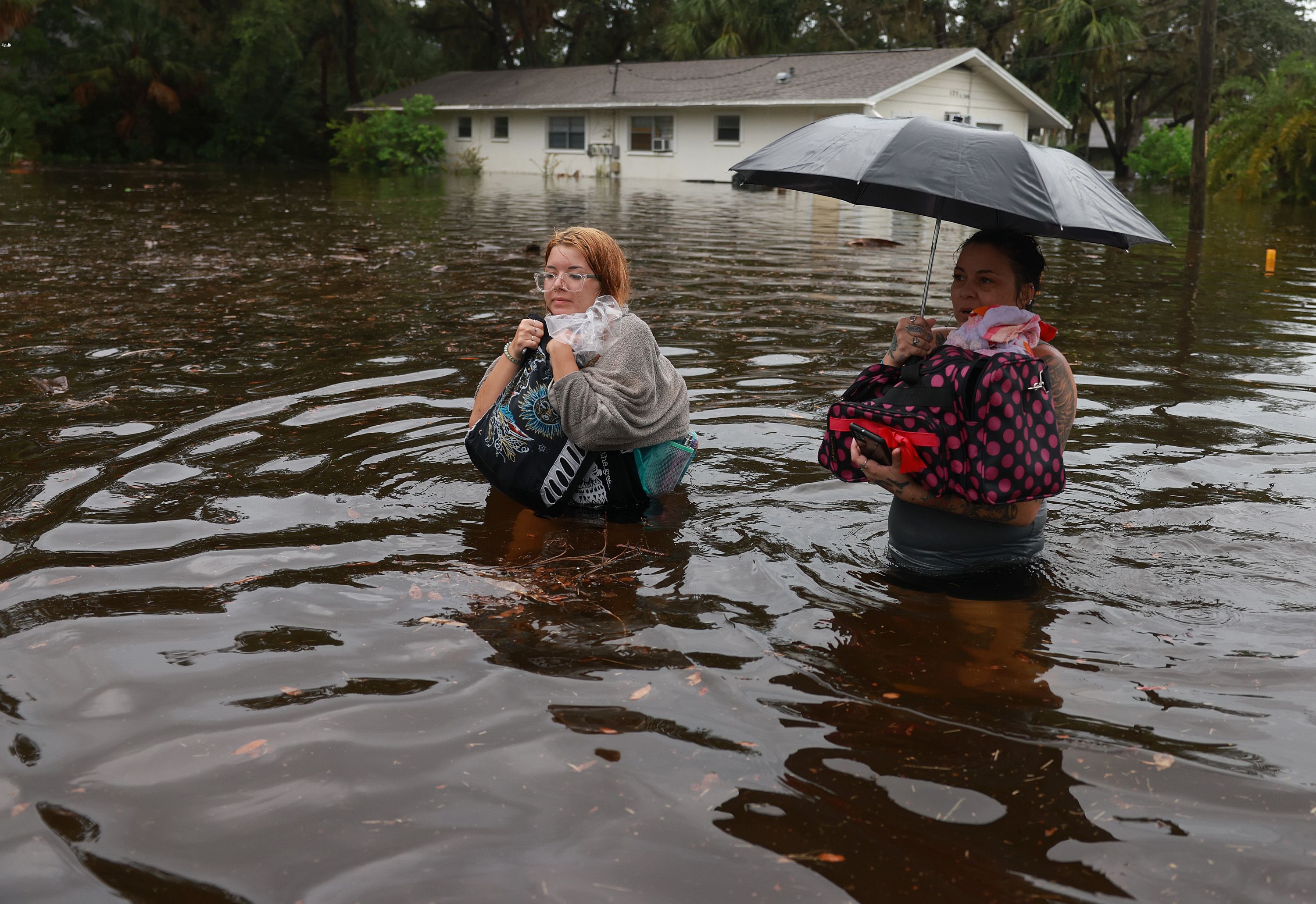 Makatla Ritchter (L) and her mother, Keiphra Line wade through flood waters after having to evacuate their home when the flood waters from Hurricane Idalia inundated it on August 30, 2023 in Tarpon Springs, Florida. 