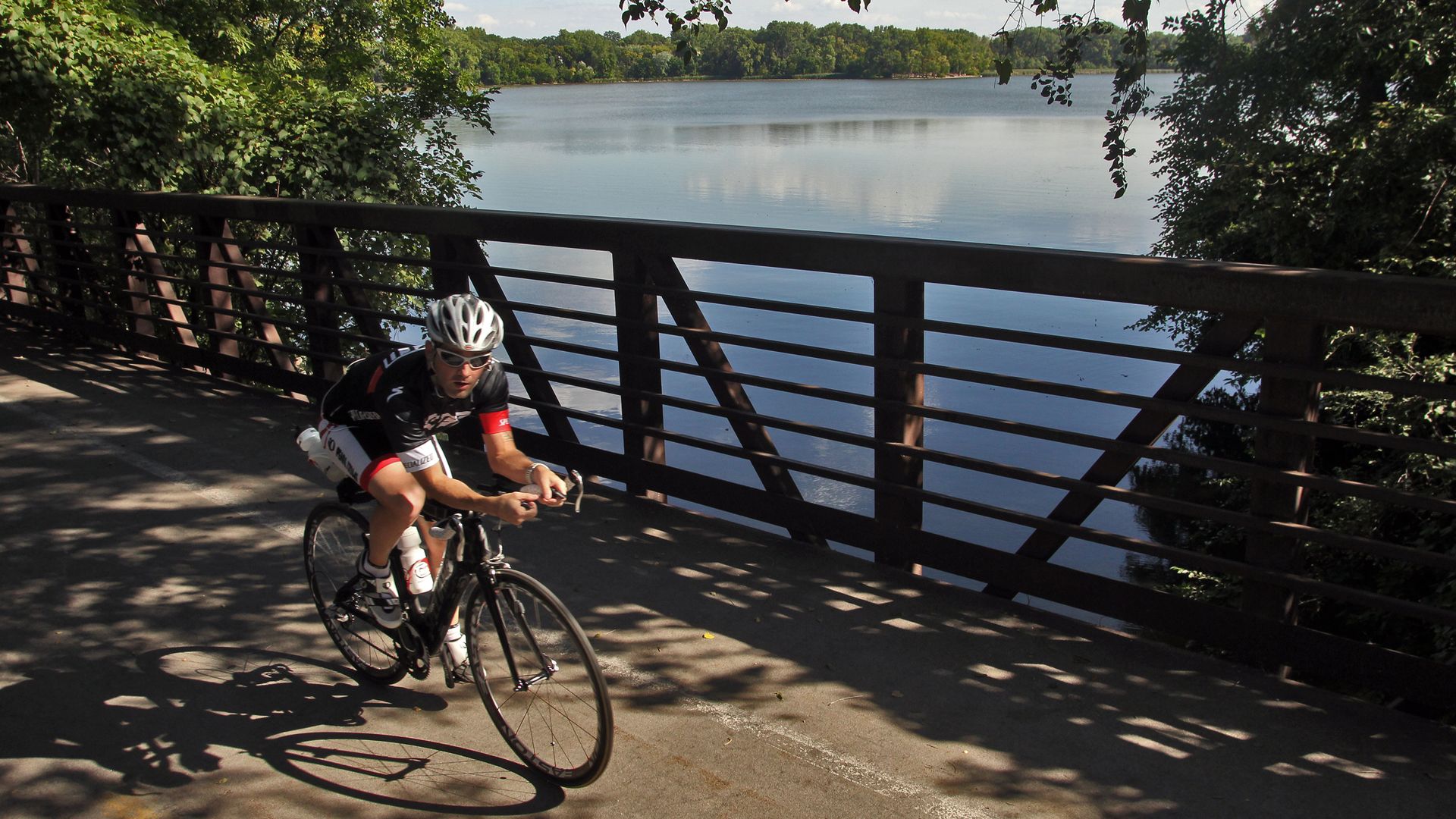 A man bikes over a bridge near a lake in Minneapolis